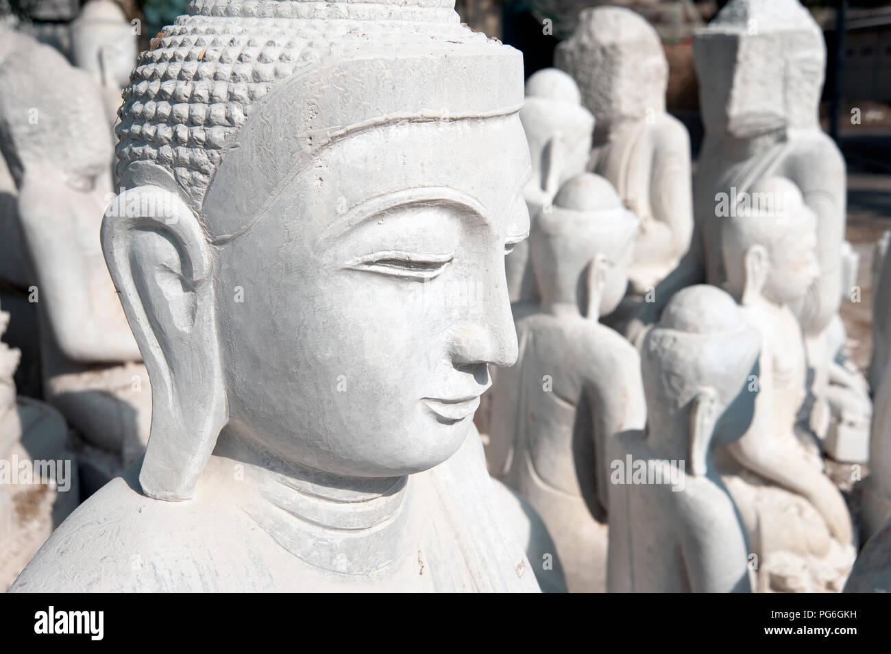 Nahaufnahme eines weißen Marmor Statue von Buddha Kopf mit weißer Marmor Buddha Statuen im Hintergrund Mandalay Myanmar Stockfoto