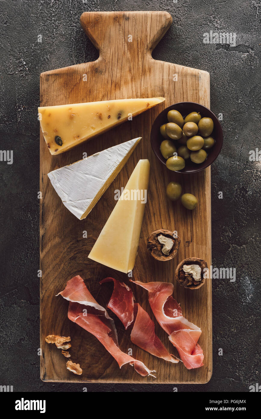 Flach mit verschiedenen Käse, Schinken und Oliven in Schale auf dunkle Oberfläche Stockfoto