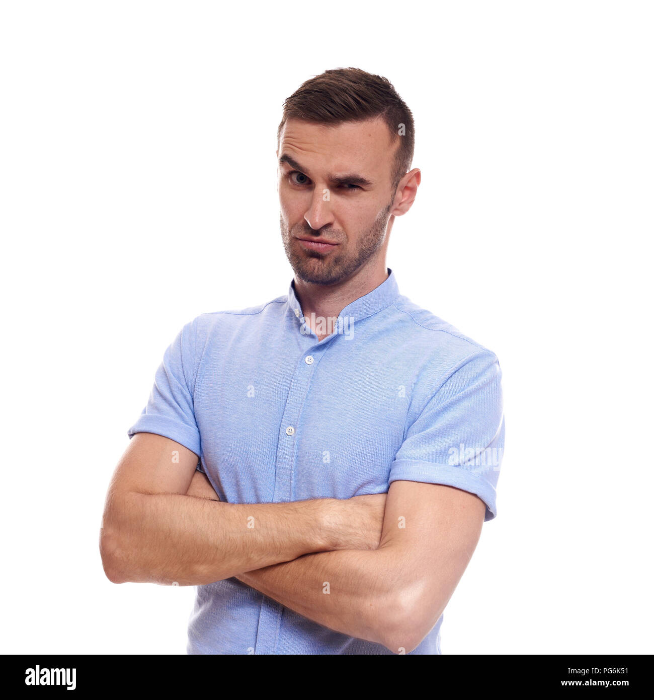 Beiläufig stattlich. Selbstbewussten jungen gutaussehenden Mann in Jeans shirt halten die Arme verschränkt und lächelnd, während gegen den weißen Hintergrund stehen. Stockfoto