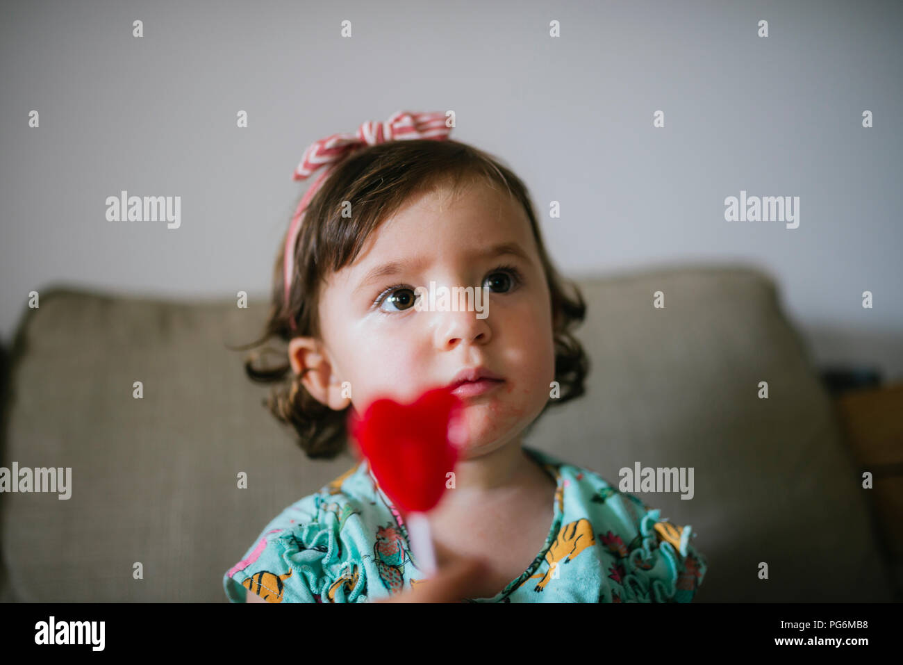 Cute Baby Mädchen essen eine herzförmige Lollipop zu Hause Stockfoto