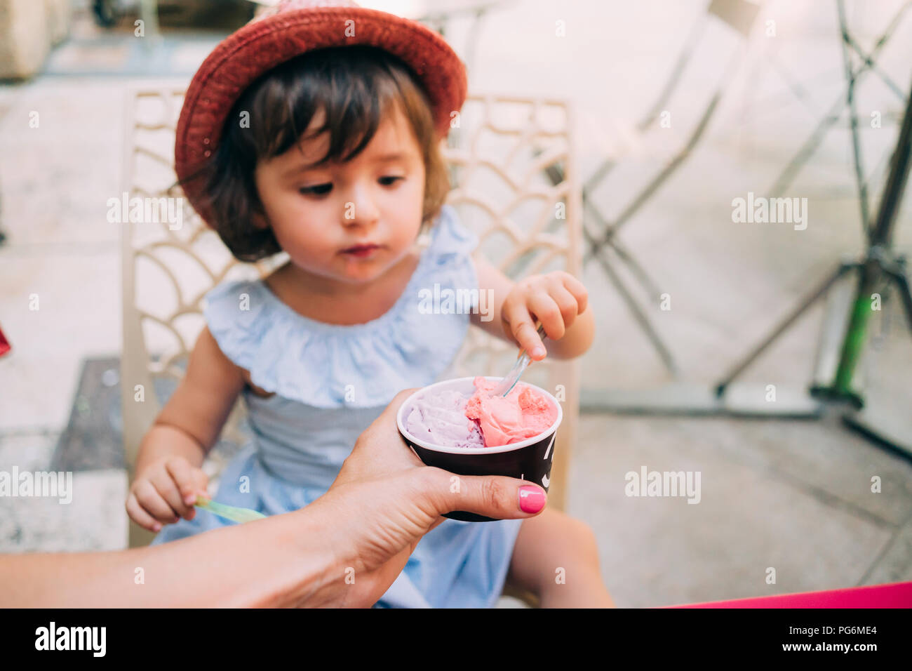 Niedliches kleinkind Mädchen essen ein Eis von ihrer Mutter gehalten Stockfoto