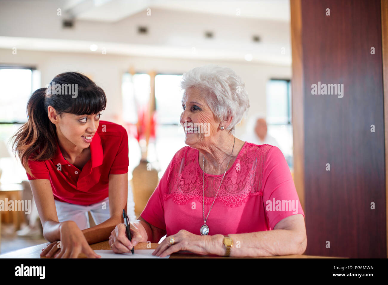 Ältere Frau einen Vertrag unterzeichnen, Krankenschwester, ihr zu helfen Stockfoto