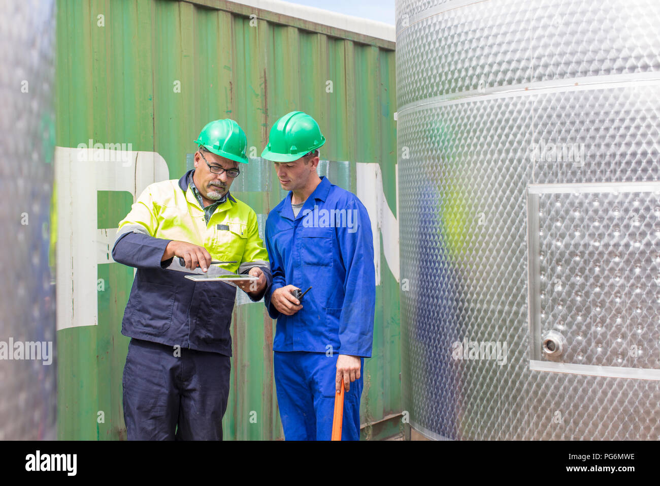 Arbeiter mit Tablet am Container im Gespräch mit Mitarbeiter Stockfoto