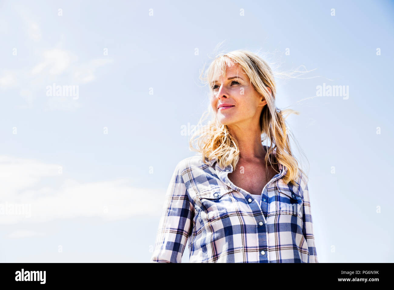 Blonde Frau tragen kariertes Hemd im Freien Stockfoto
