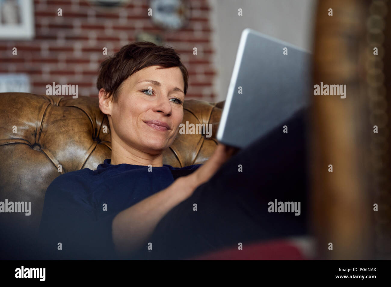 Woamn sitzen auf dem Sofa zu Hause, mit digitalen Tablet Stockfoto
