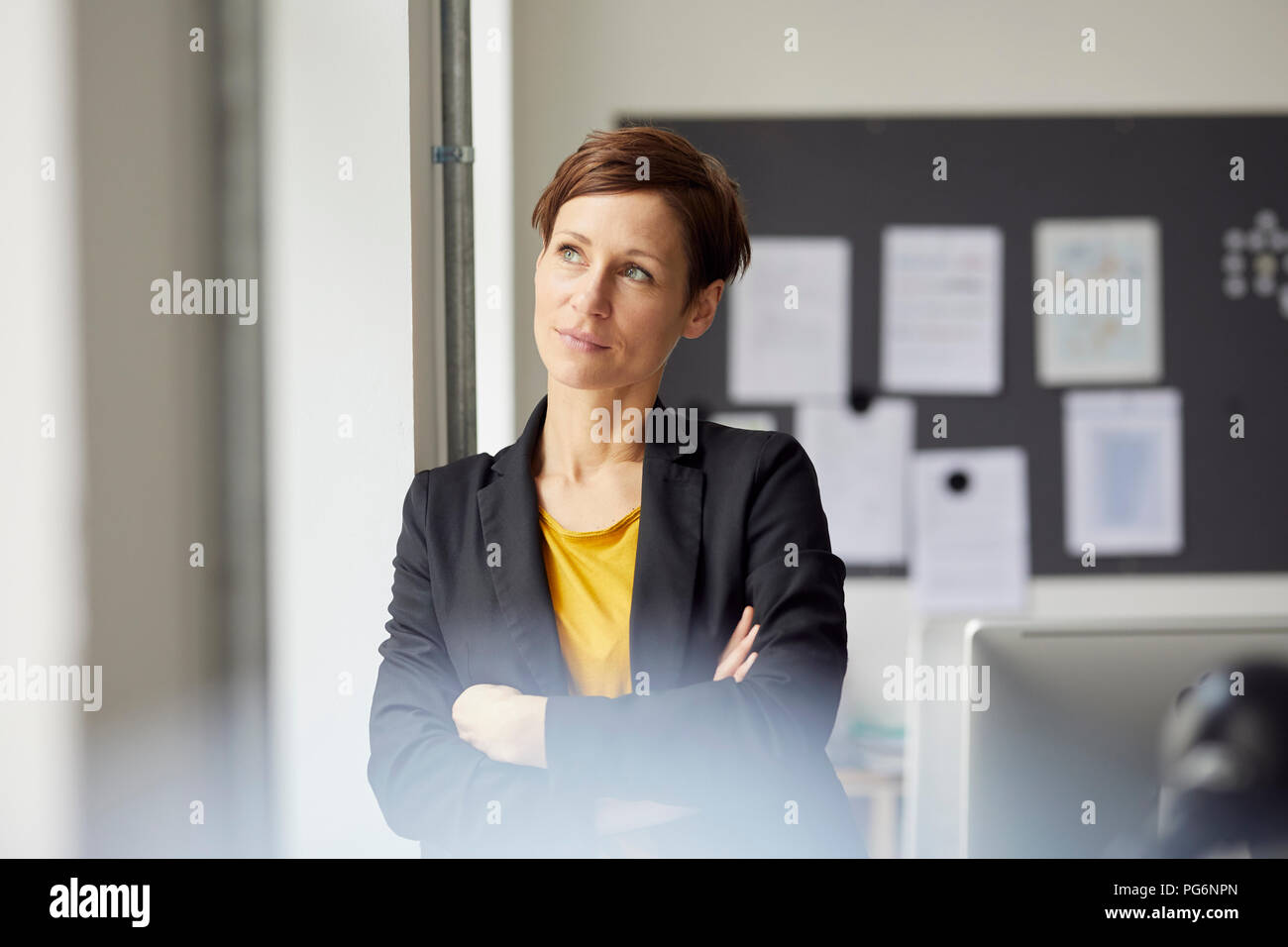 Attraktive Geschäftsfrau im Büro mit gekreuzten Armen Stockfoto