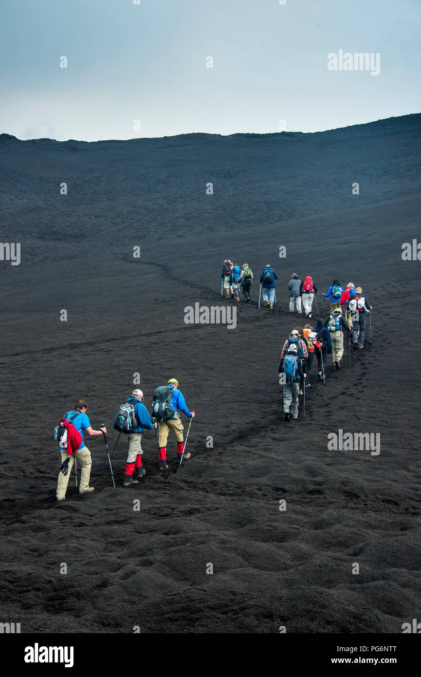 Touristen zu Fuß in einer Linie durch die Lava des Vulkans Tolbachik, Kamtschatka, Russland Stockfoto