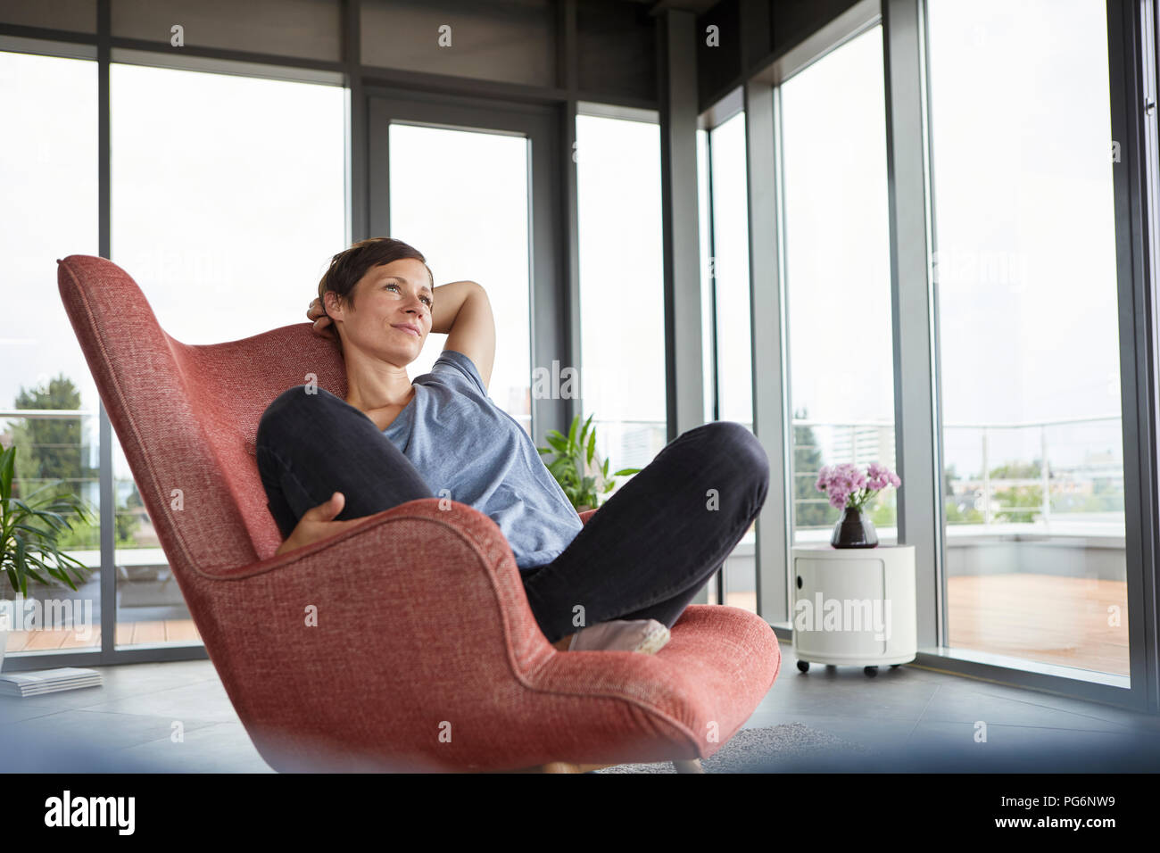 Frau sitzt im Sessel zu Hause entspannen Stockfoto