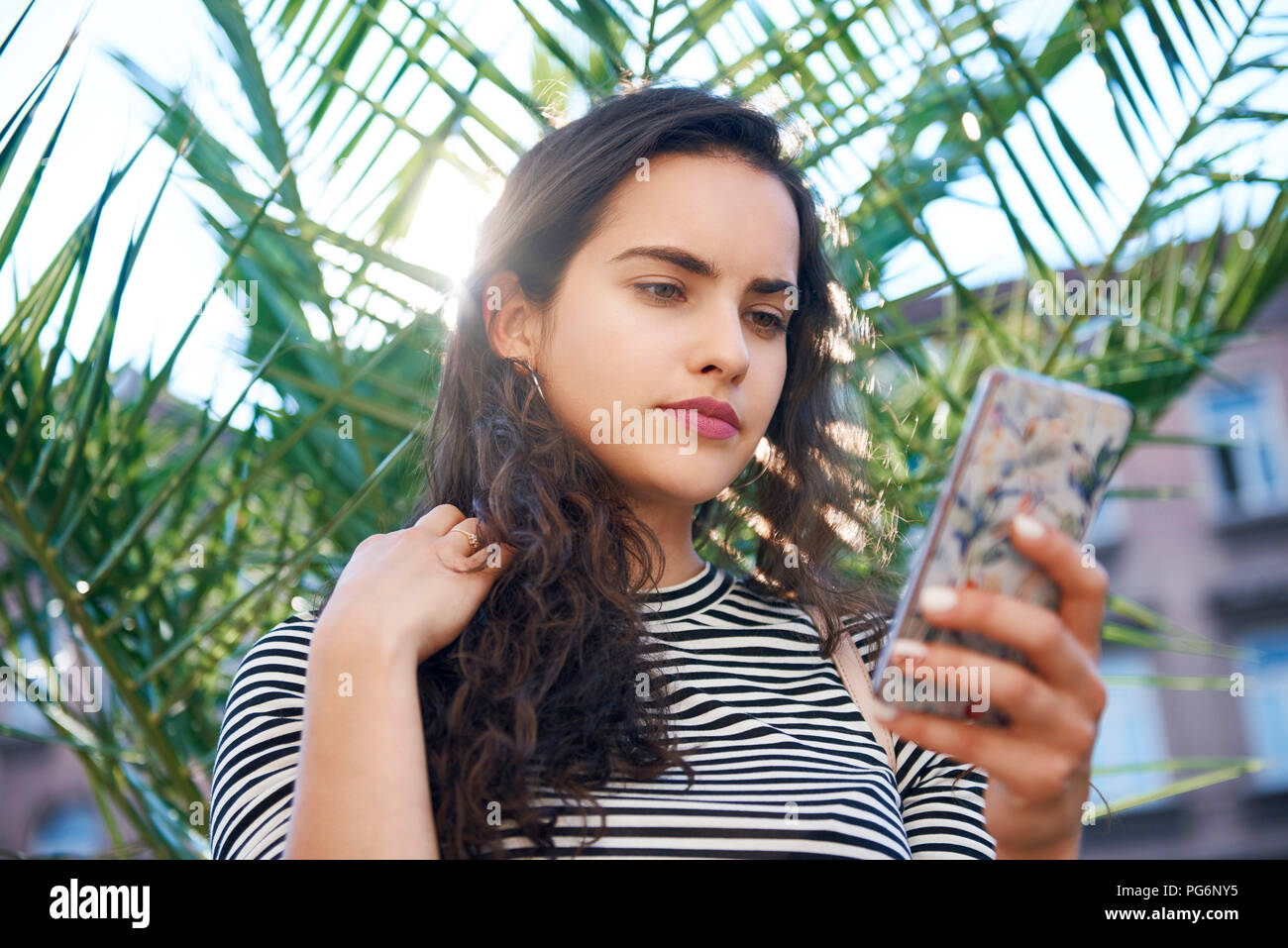 Junge Frau mit Handy vor einer Anlage Stockfoto