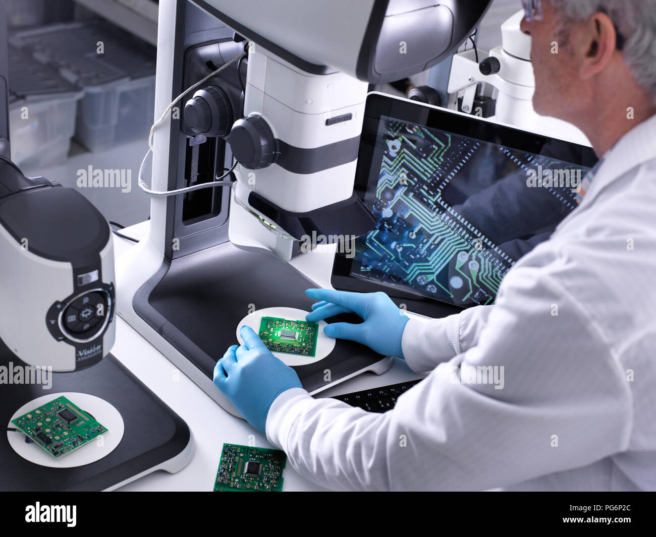 Techniker mit Hilfe eines 3-D Stereo Mikroskop für die Qualitätskontrolle in der Herstellung von Platinen für die Elektronikindustrie Stockfoto