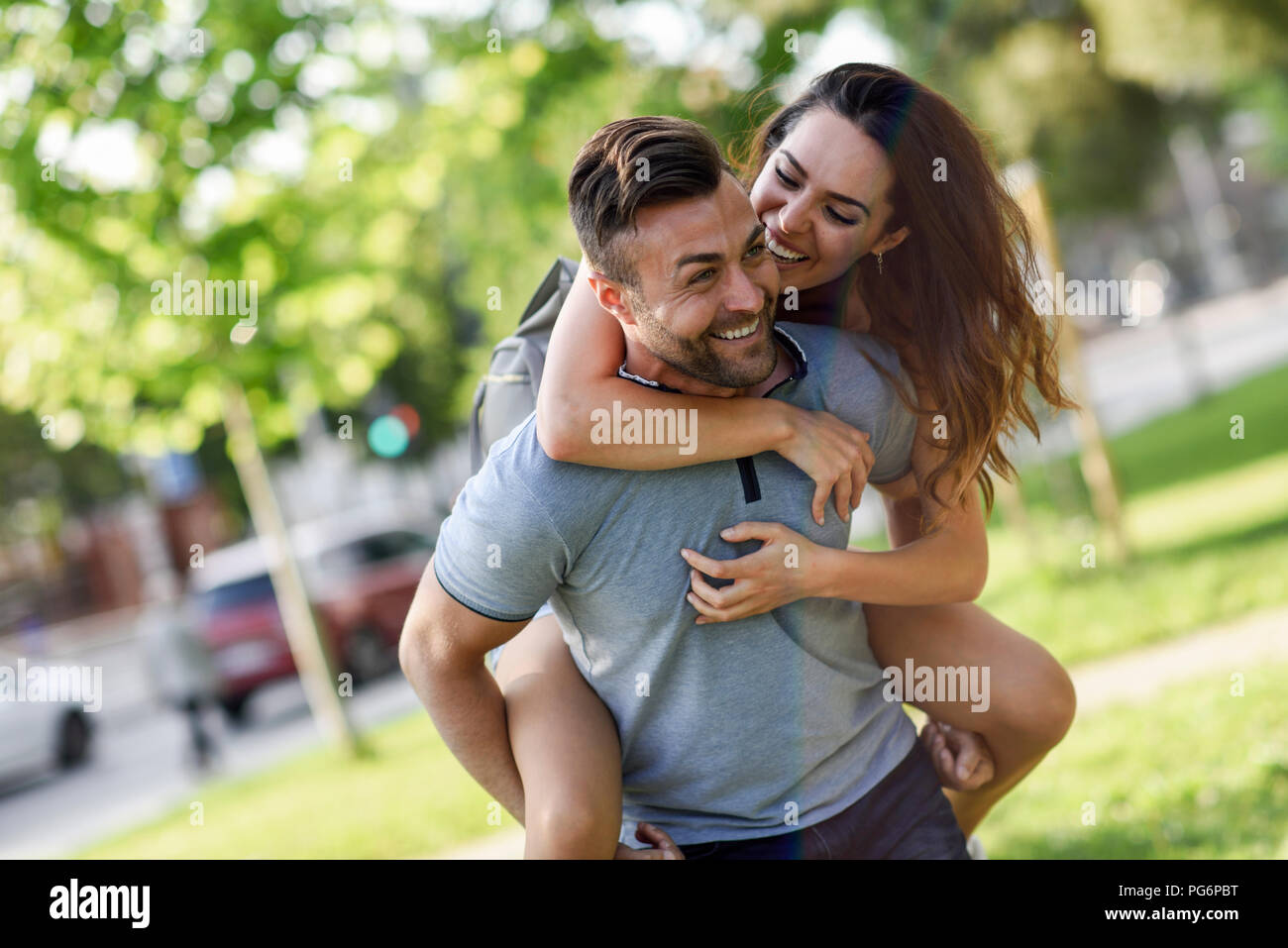 Glücklicher Mann geben Freundin eine Huckepack Fahrt im park Stockfoto