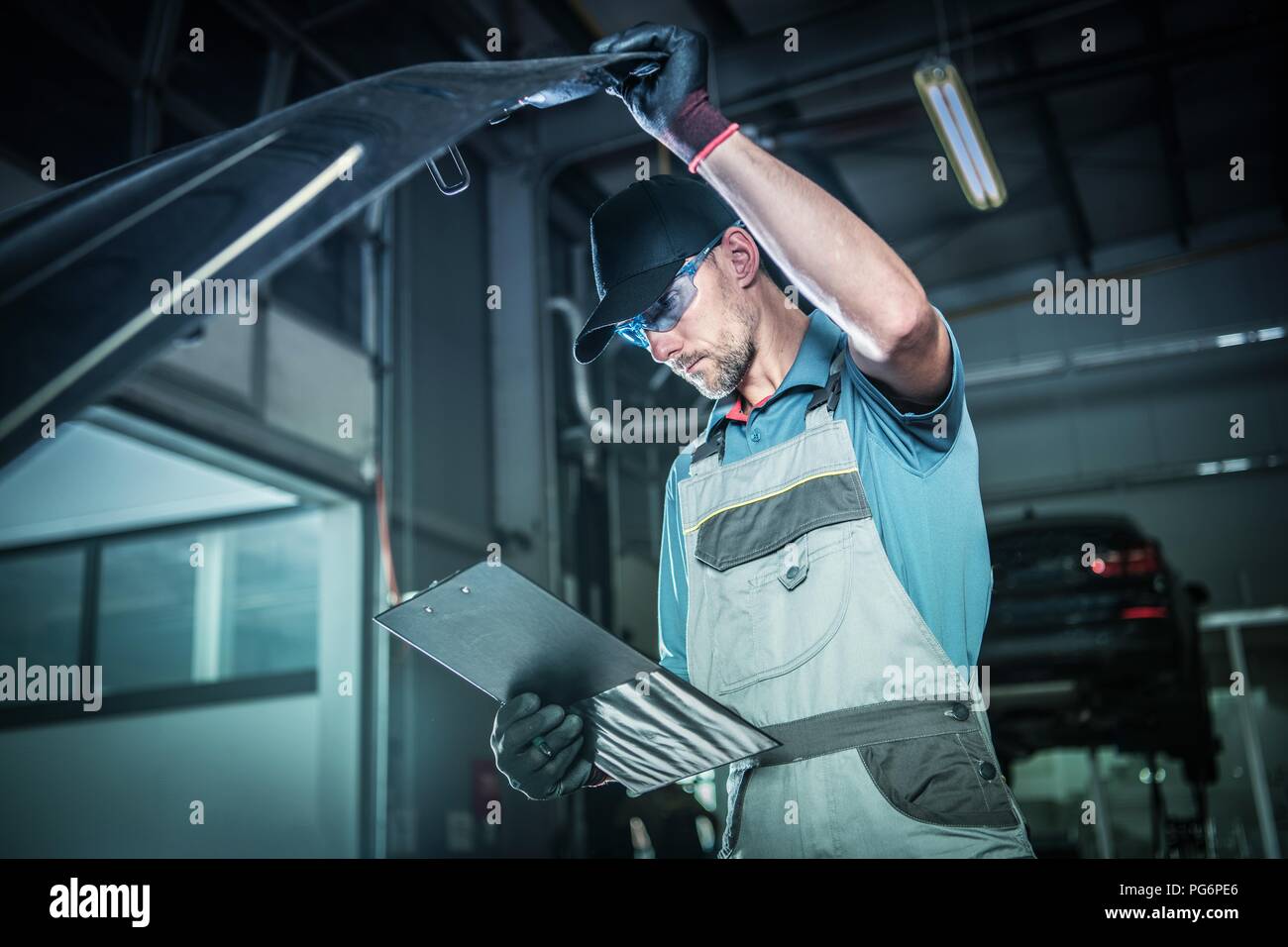 Motor Problem. Kaukasische Techniker in seinem 30s im Inneren Händler Service Bereich unter Detaillierte Inspektion unter dem Auto Haube. Automobilindustrie. Stockfoto