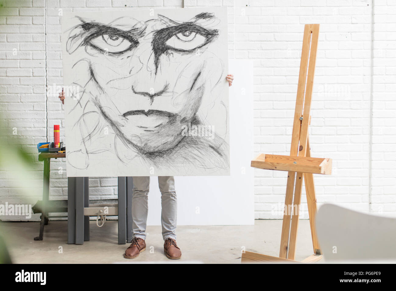Verdeckt Künstler hinter Leinwand holding Zeichnung im Studio Stockfoto