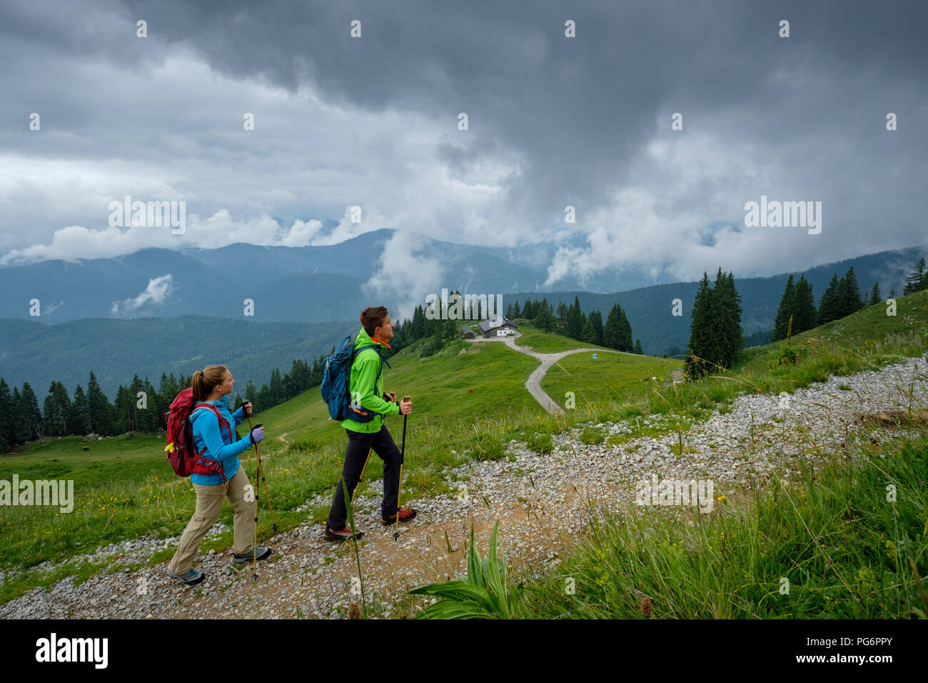 Deutschland, Lenggries, junges Paar mit Wanderstöcken wandern nach oben Stockfoto