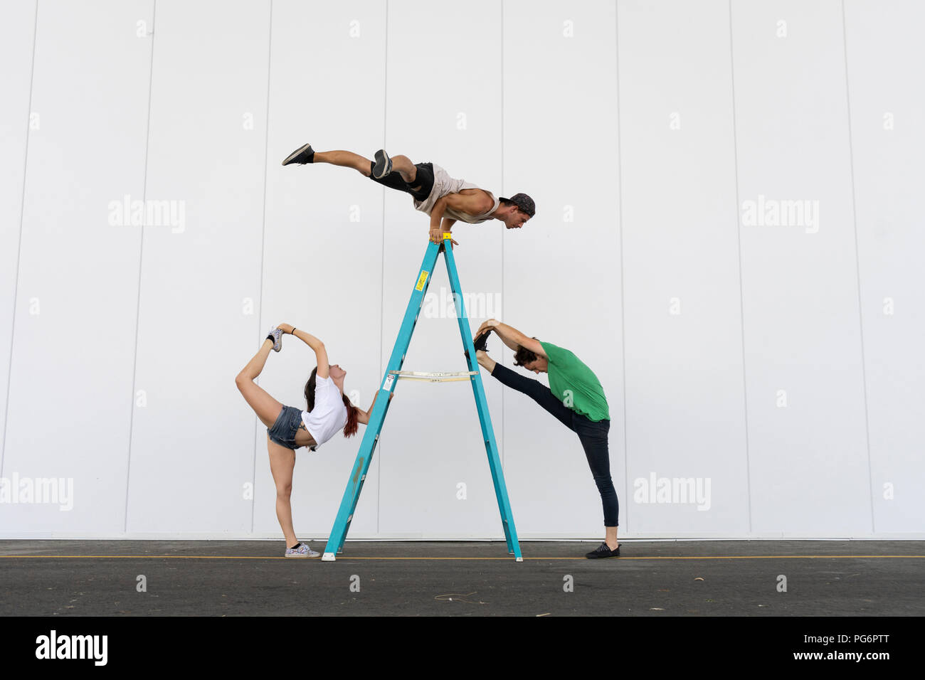 Drei Akrobaten Tricks auf einer Leiter Stockfoto