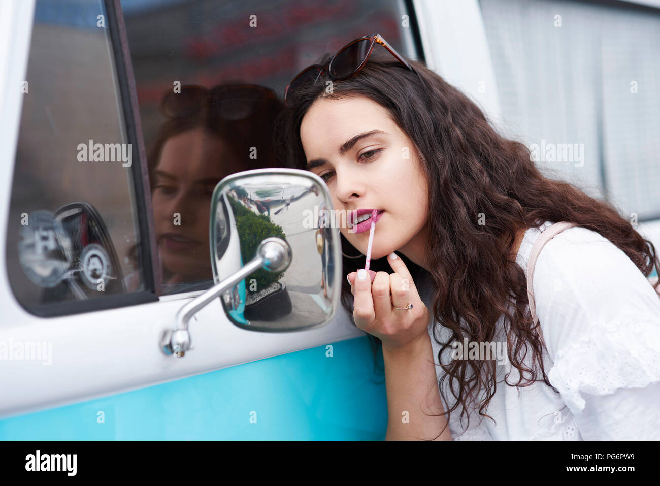 Junge Frau Anwendung Lippenstift suchen im Rückspiegel eines van Stockfoto
