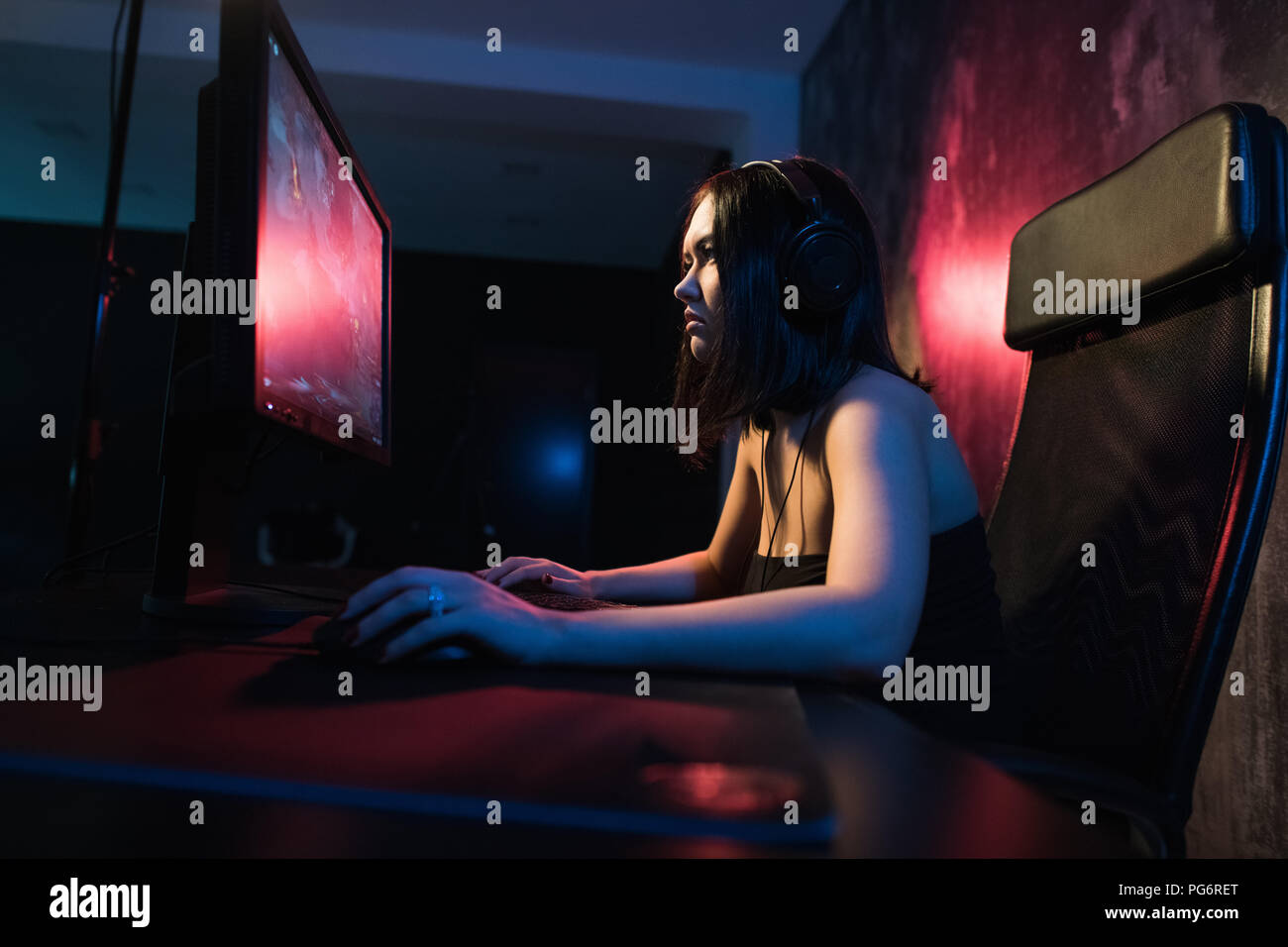 Girl Gamer in Kopfhörern und mit Tastatur und Maus in die Hände spielen Netzwerk Spiele vorbereiten bei internationalen Wettbewerben in den e-Sport teilnehmen Stockfoto
