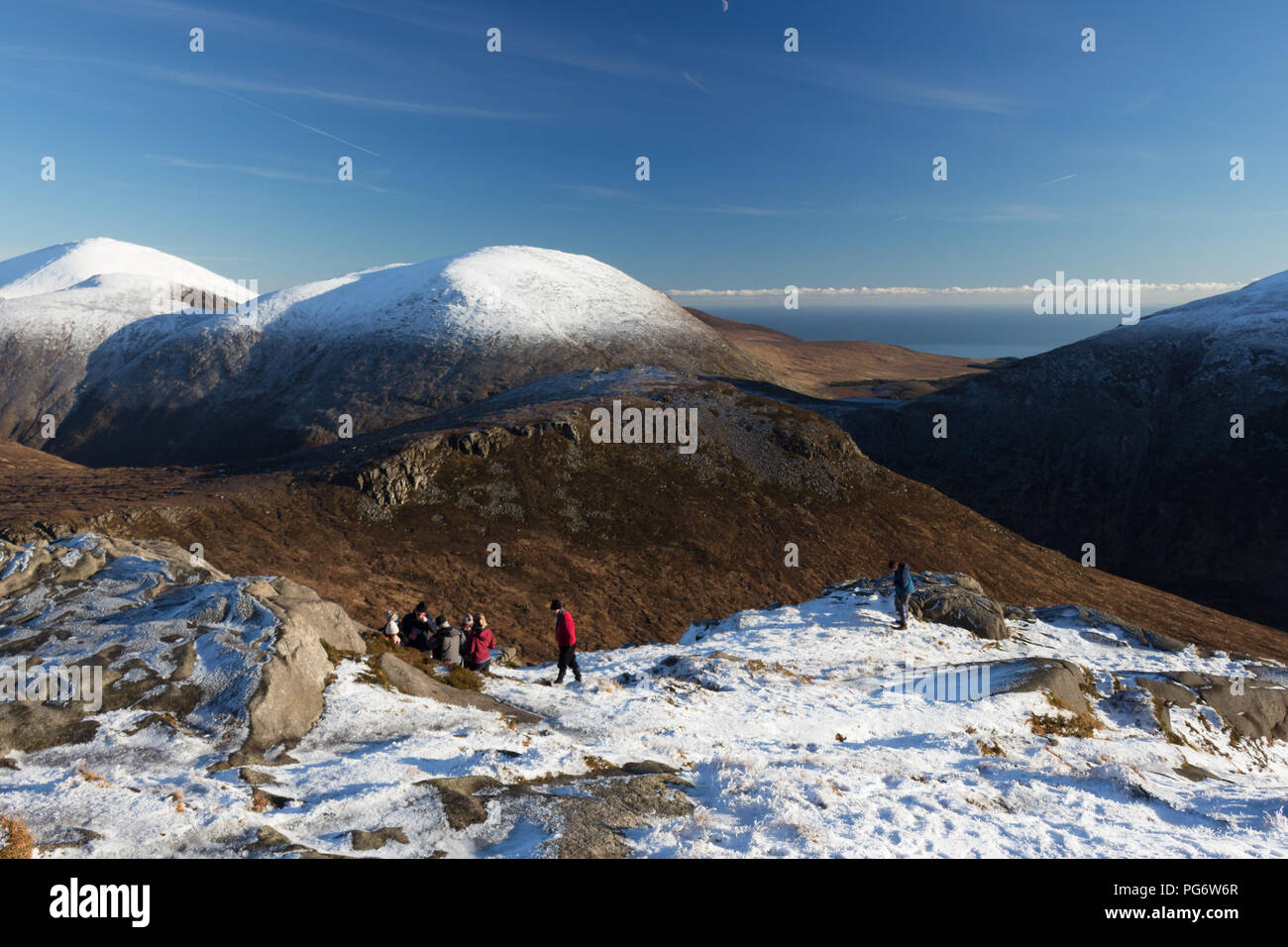 Gruppe von Winter hillwalkers genießen einen Rest auf Doan Berg. Blick auf Ben Crom direkt vor und schneebedeckten Lamagan hinter sich. Slieve Donard auf der linken Seite. Stockfoto