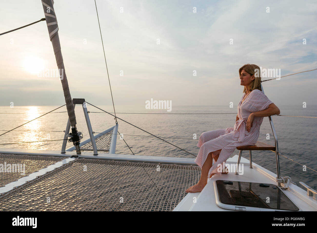 Reife Frau auf Katamaran, Sonnenuntergang beobachten Stockfoto
