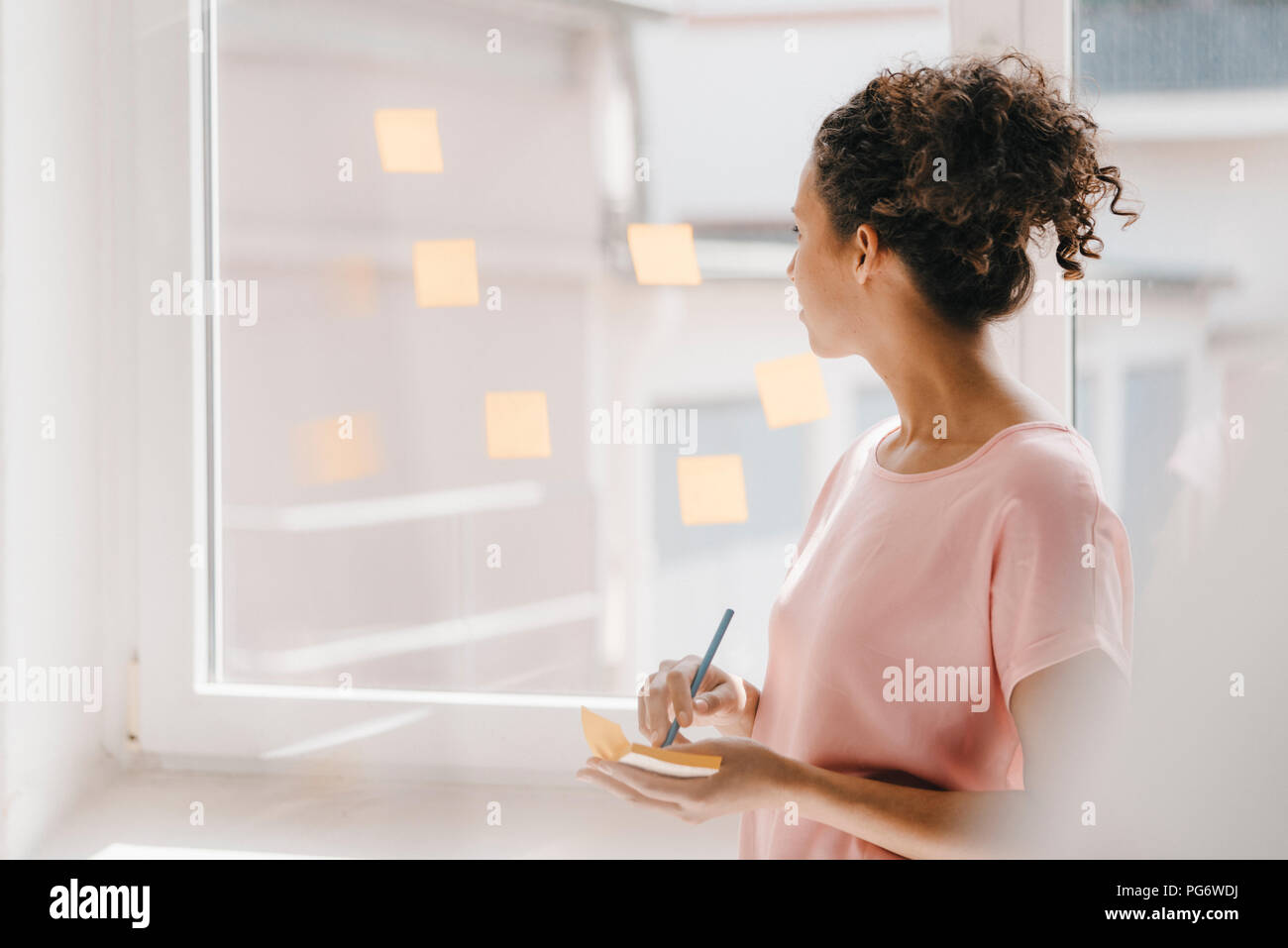 Frau buchung Haftnotizen auf Fenster, Brainstorming Stockfoto