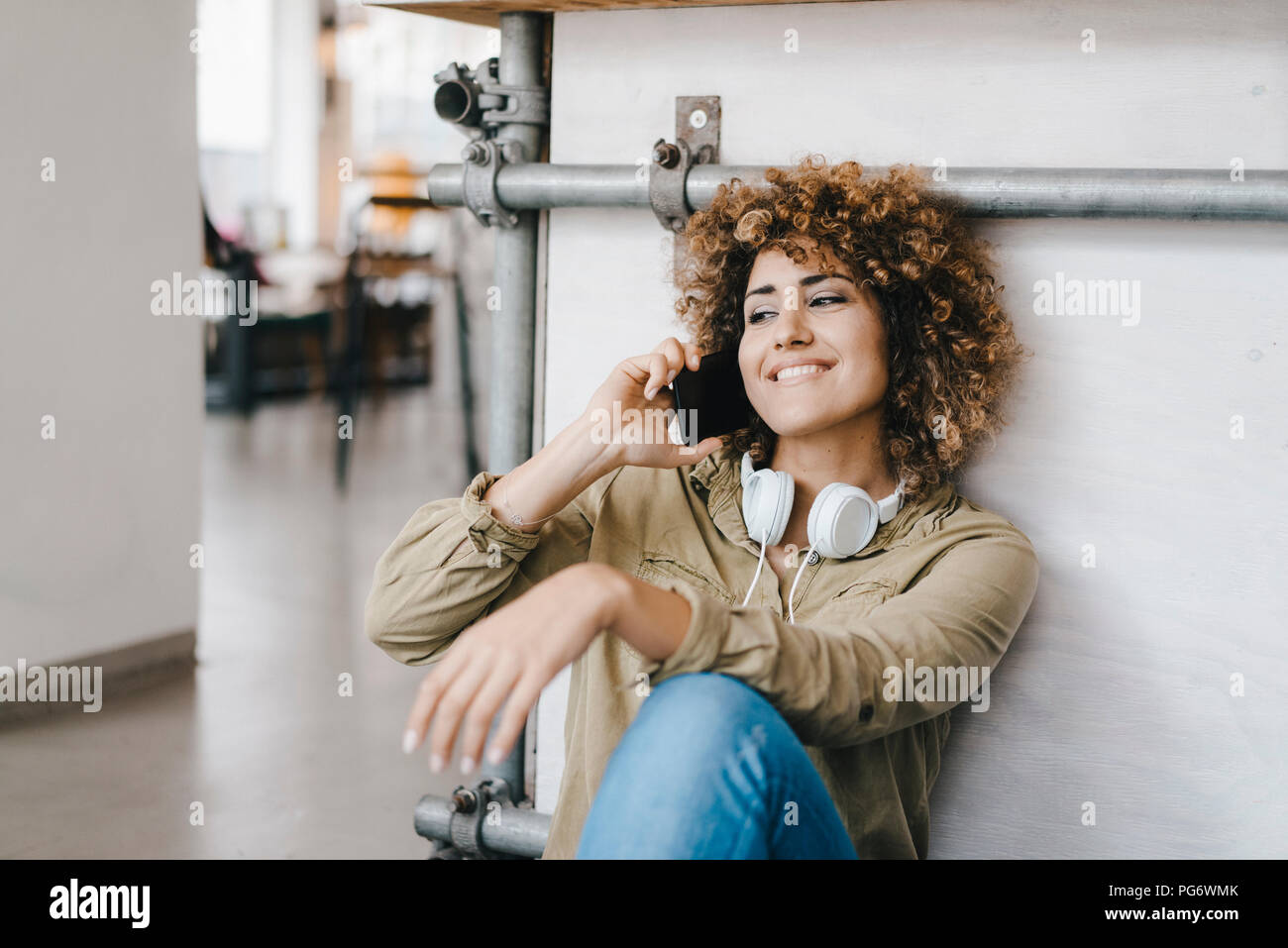 Junge Frau mit Kopfhörer, arbeiten in Coworking Space, Telefonieren Stockfoto