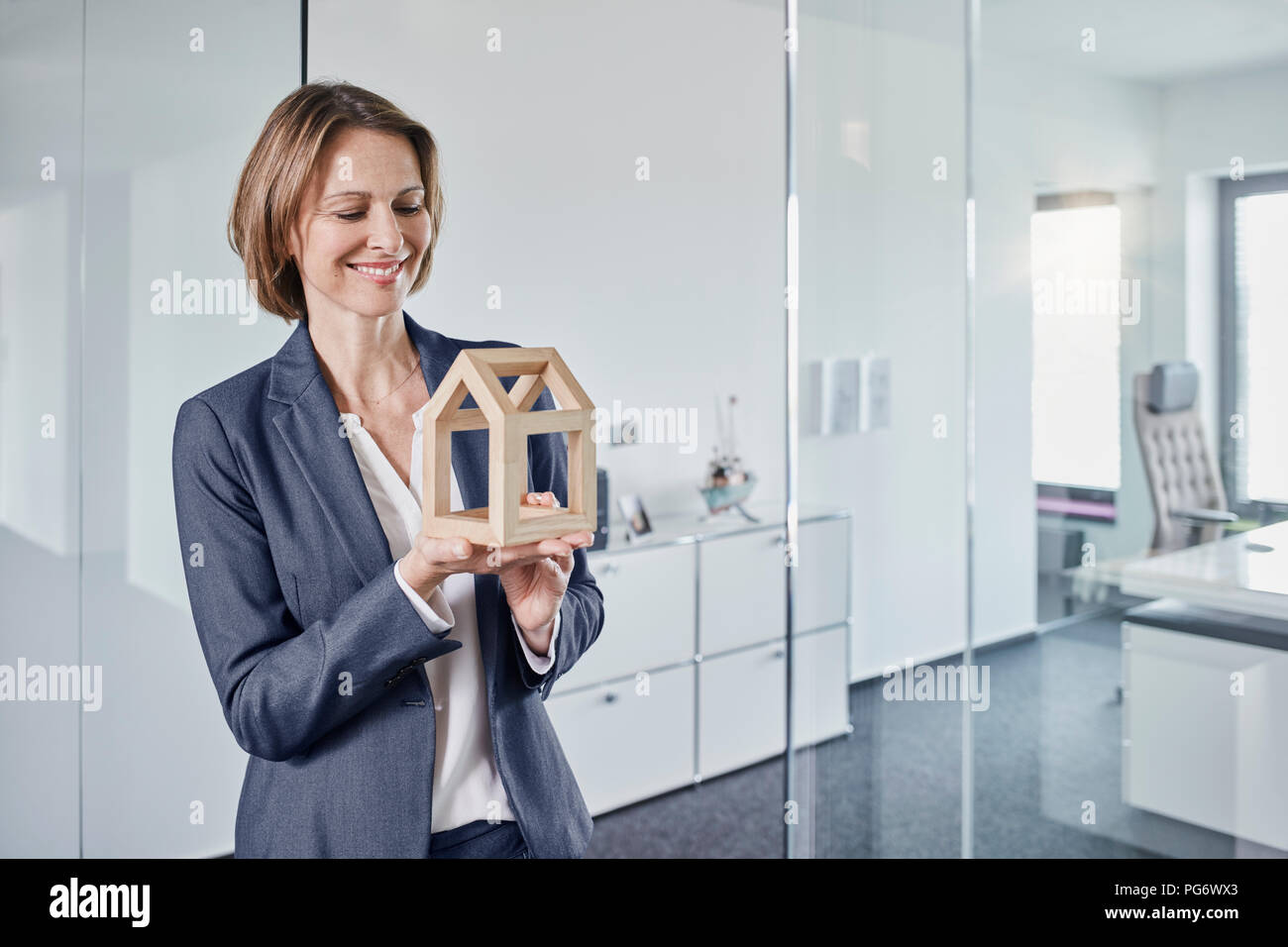 Lächelnd geschäftsfrau am Architekturmodell im Büro suchen Stockfoto