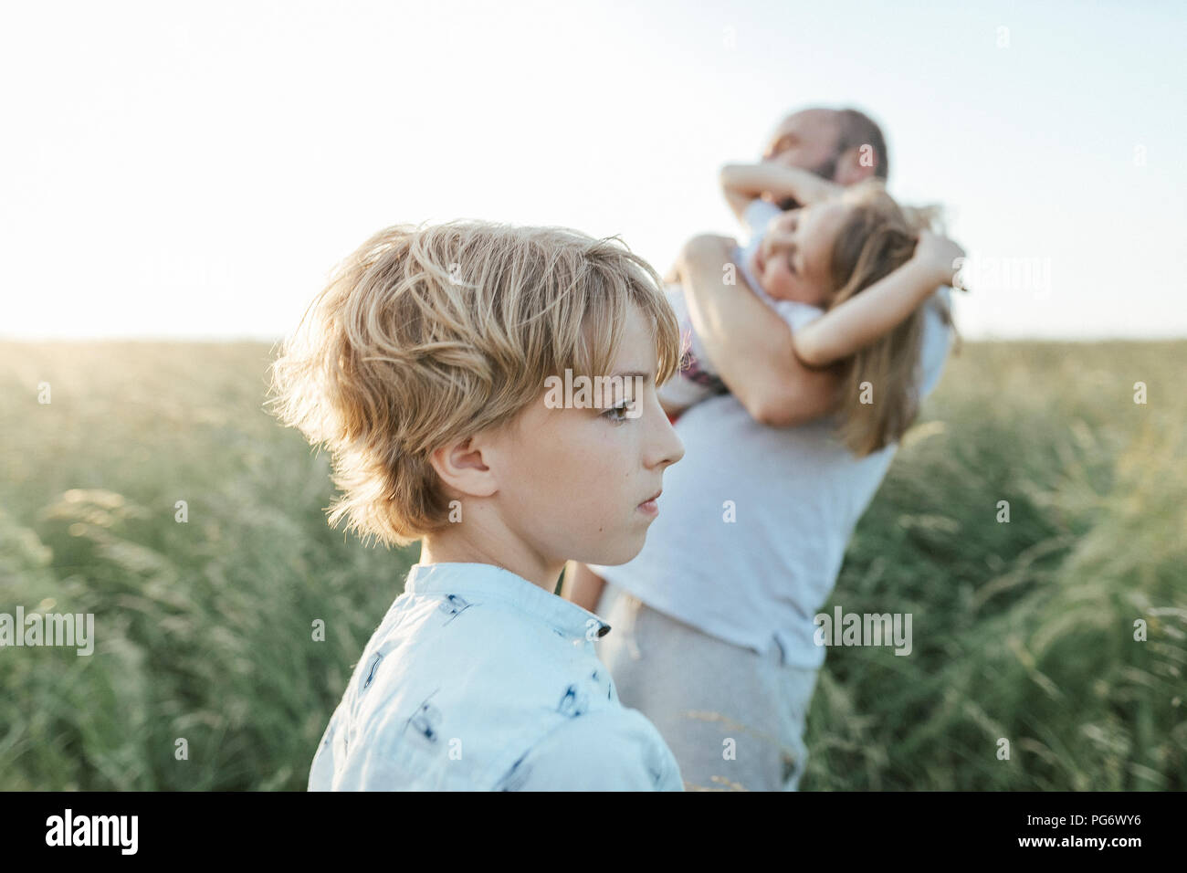 Traurige Junge mit Vater und Schwester spielen gemeinsam im Hintergrund Stockfoto
