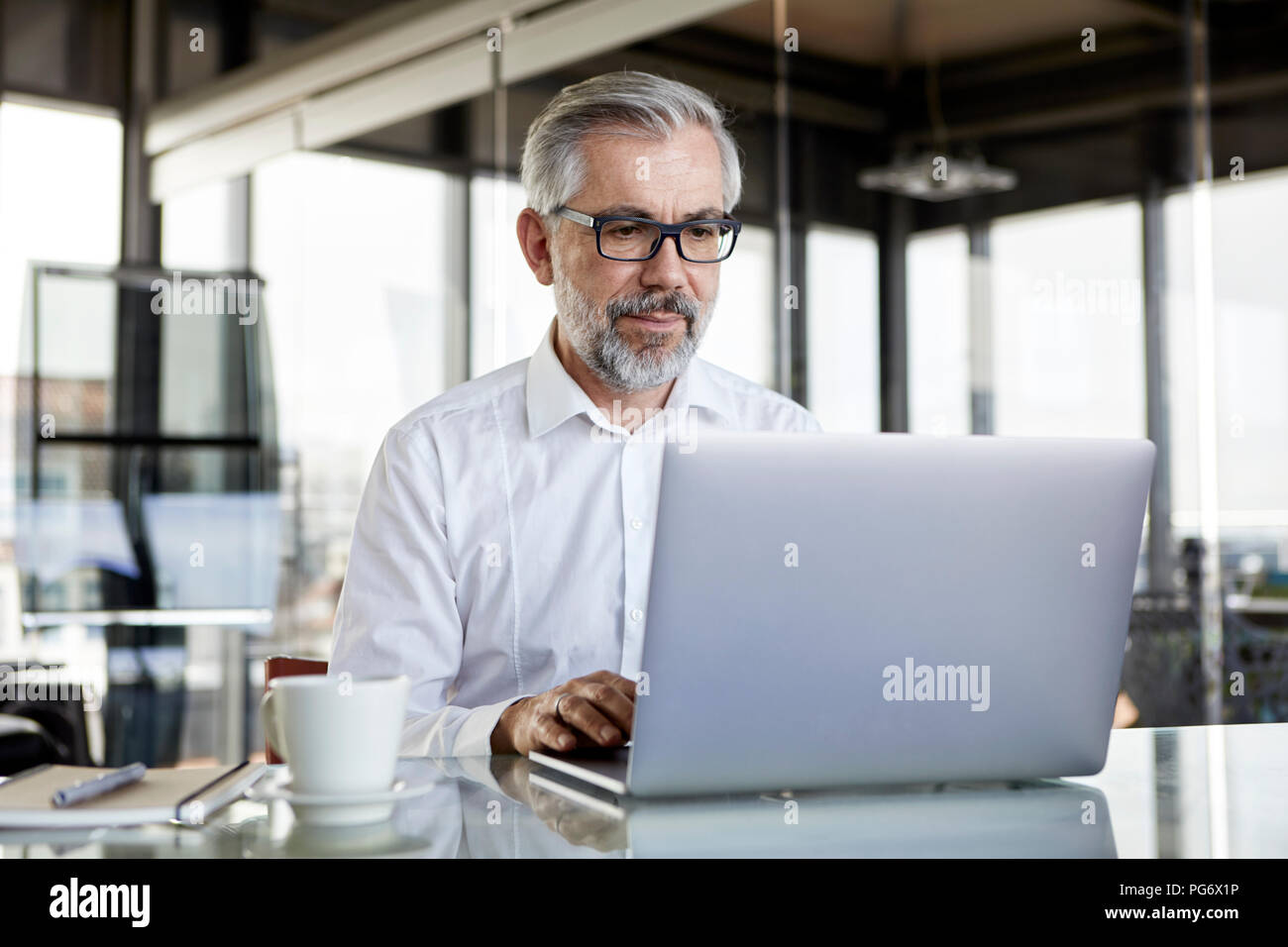 Geschäftsmann mit Laptop am Schreibtisch im Büro Stockfoto