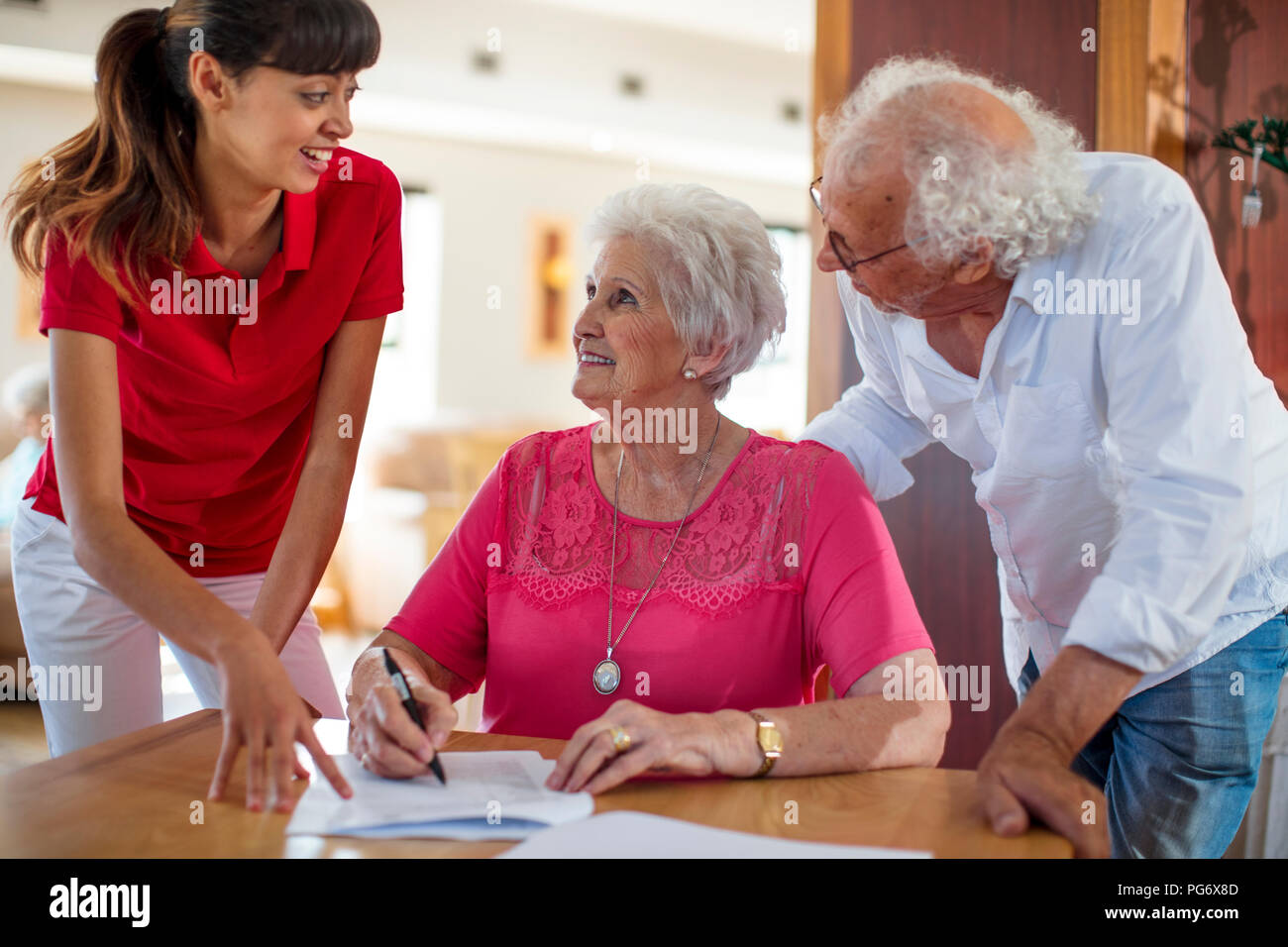 Ältere Frau einen Vertrag unterzeichnen, Krankenschwester und älterer Mann ihr zu helfen Stockfoto