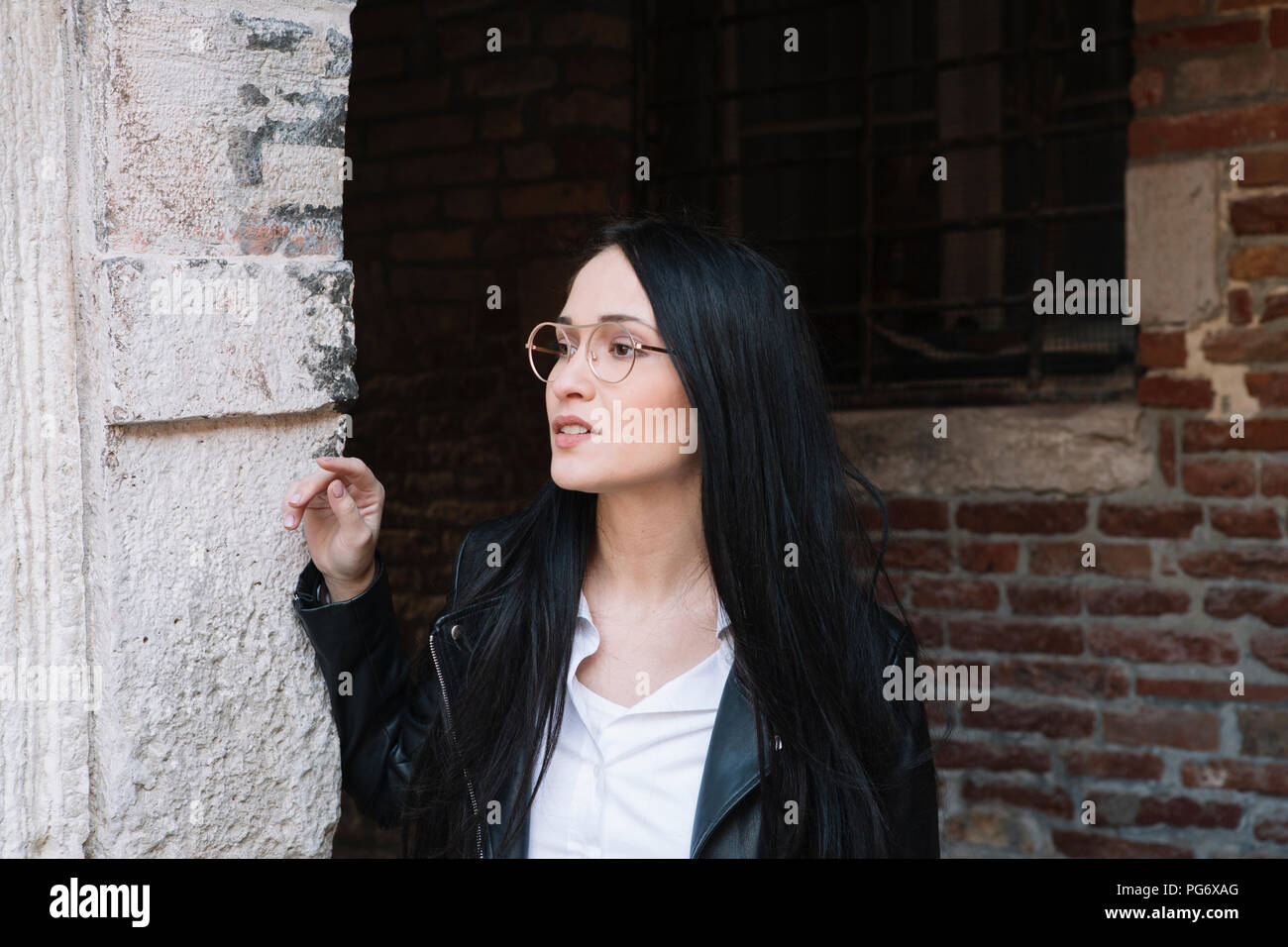 Junge Frau von alten Backsteingebäude auf der Suche Stockfoto