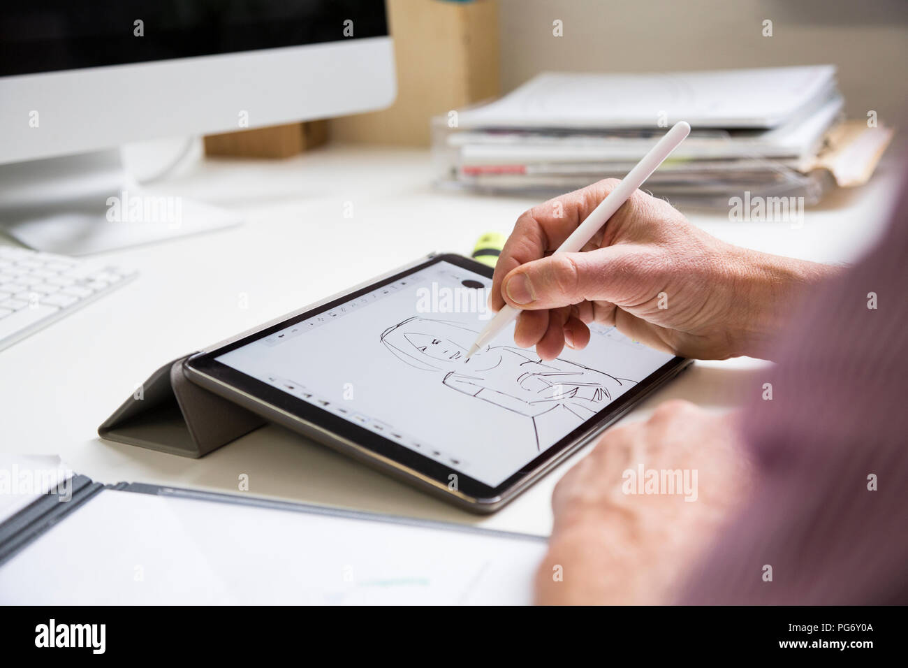 Nahaufnahme der Mann am Schreibtisch arbeiten im Büro Zeichnung weibliche Figur auf Tablet Stockfoto