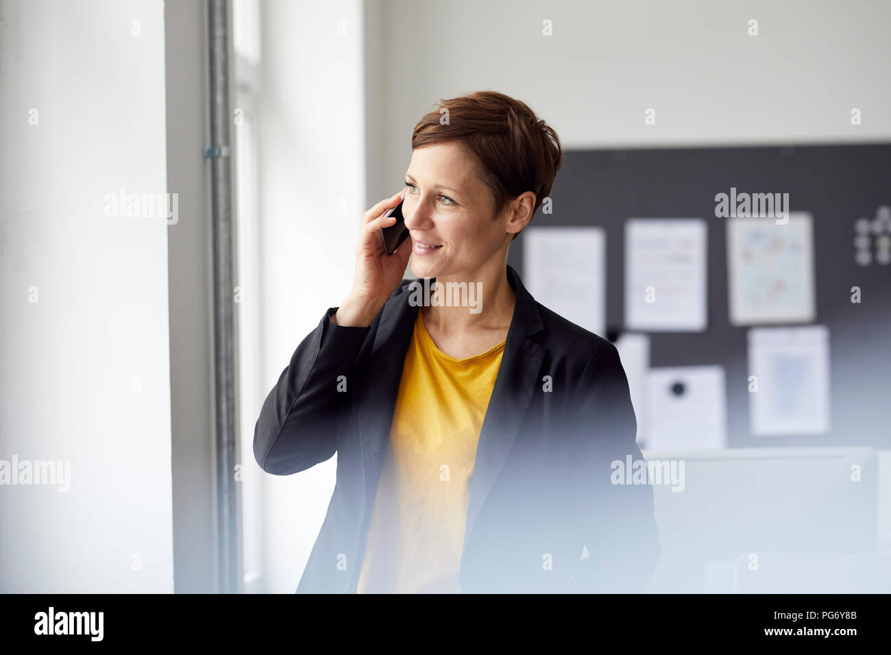 Attraktive Geschäftsfrau, die in Büros über Smartphone Stockfoto
