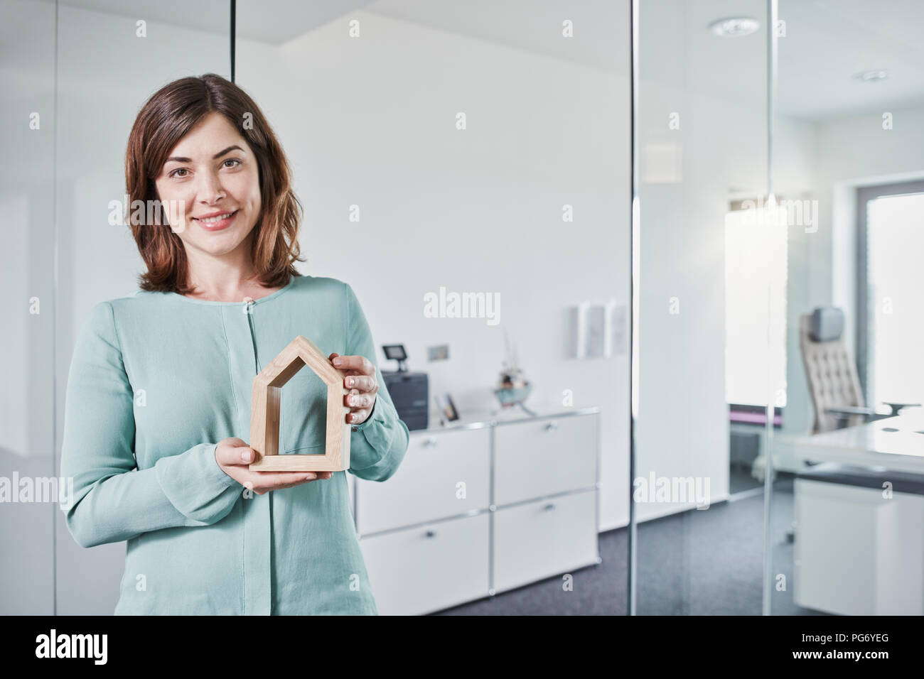 Portrait von lächelnden jungen Geschäftsfrau holding Architekturmodell im Büro Stockfoto