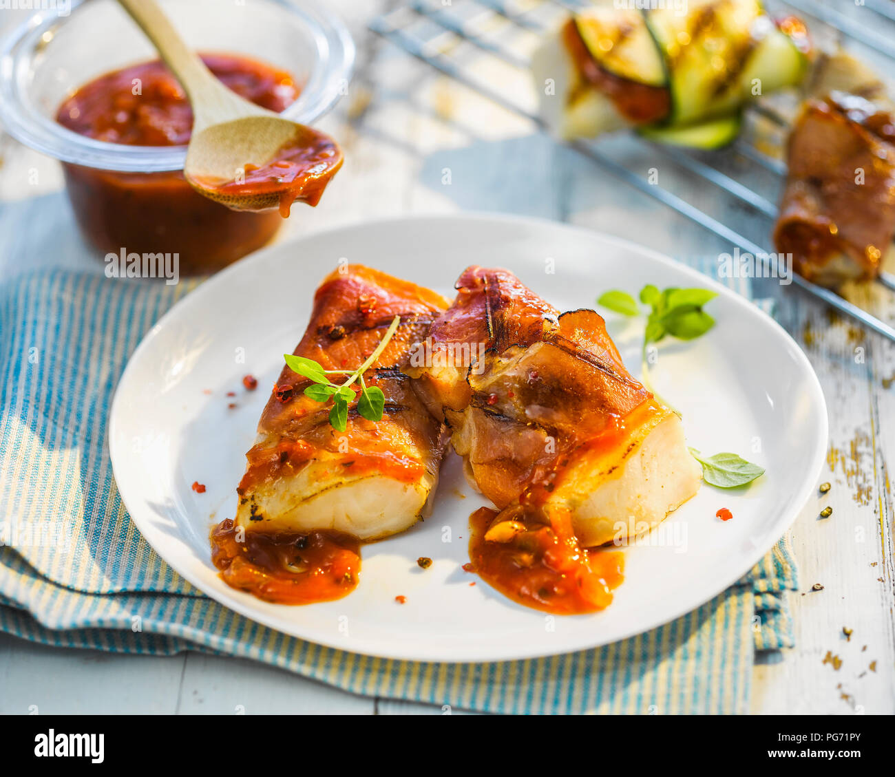 Gegrillter Fisch Filet mit Speck, Paprika Marinade und Kräuter Stockfoto