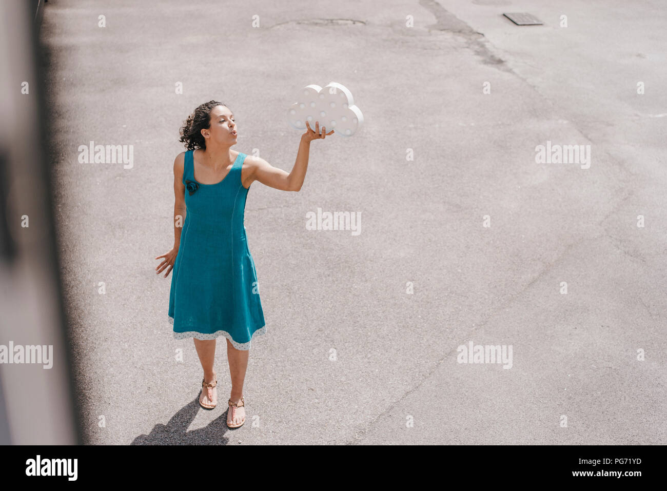 Frau, die in den Hinterhof, Holding cloud Symbol, Blasen küssen Stockfoto