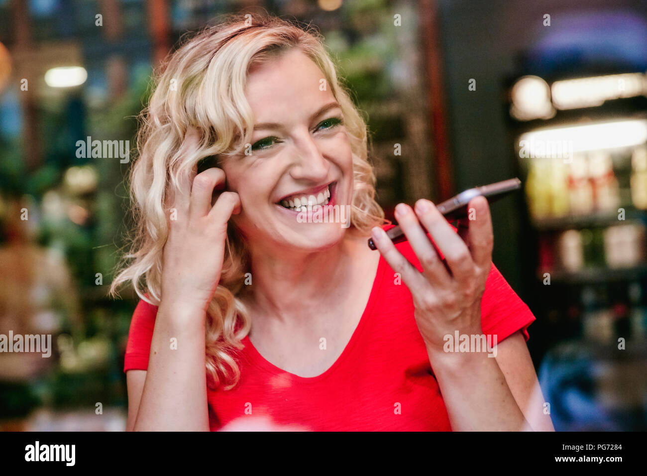 Portrait von Happy blonde Frau mit Smartphone in einem Cafe Stockfoto