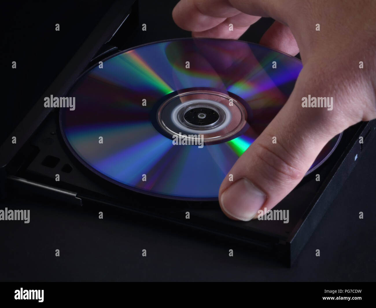 Eine glänzende und neuen DVD oder CD wird von Hand in ein optisches Media Player in einer Detailansicht geladen. Stockfoto