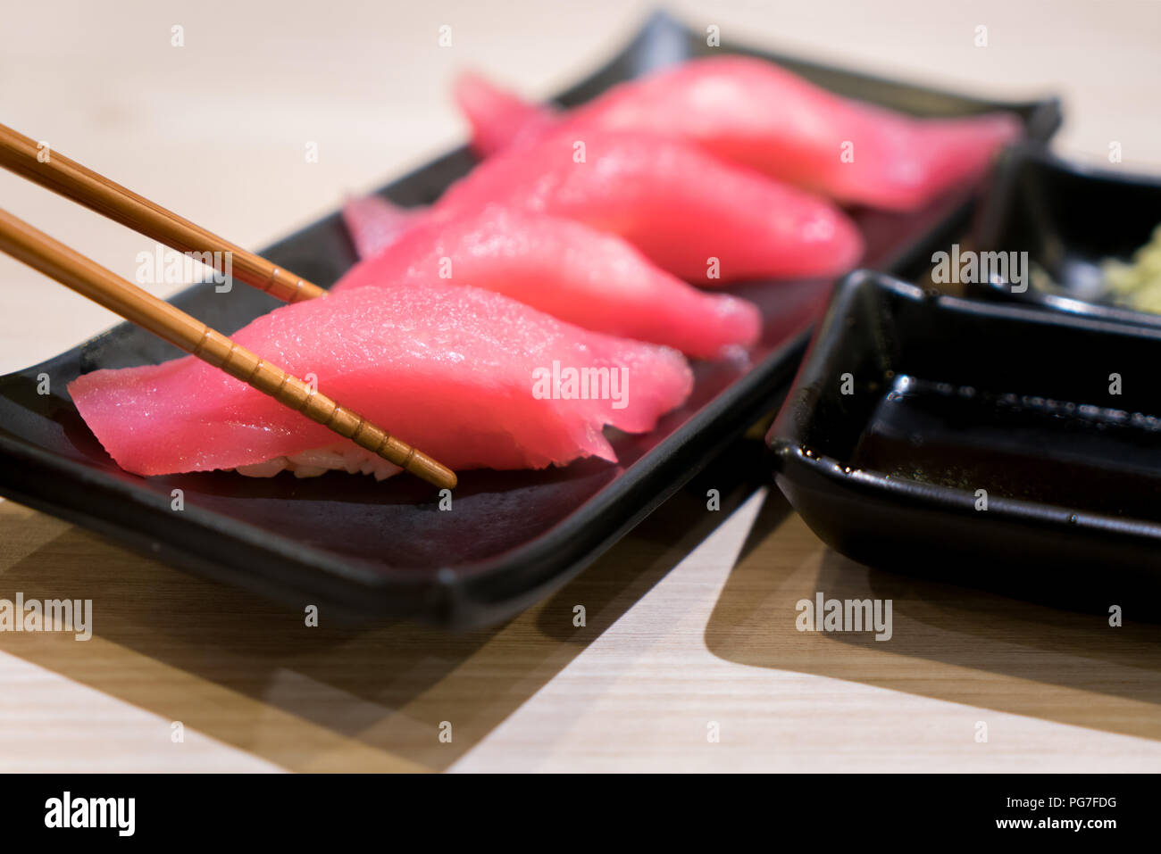 Vier Thunfisch Sushi mit Stäbchen in schwarz Platte auf dem Tisch im japanischen Restaurant. Stockfoto