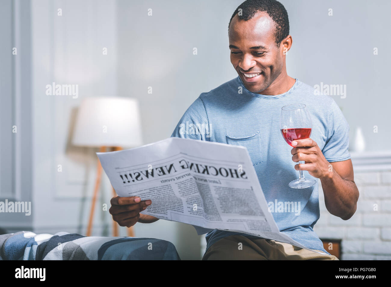 Lächelnder Mann liest Zeitung Stockfoto