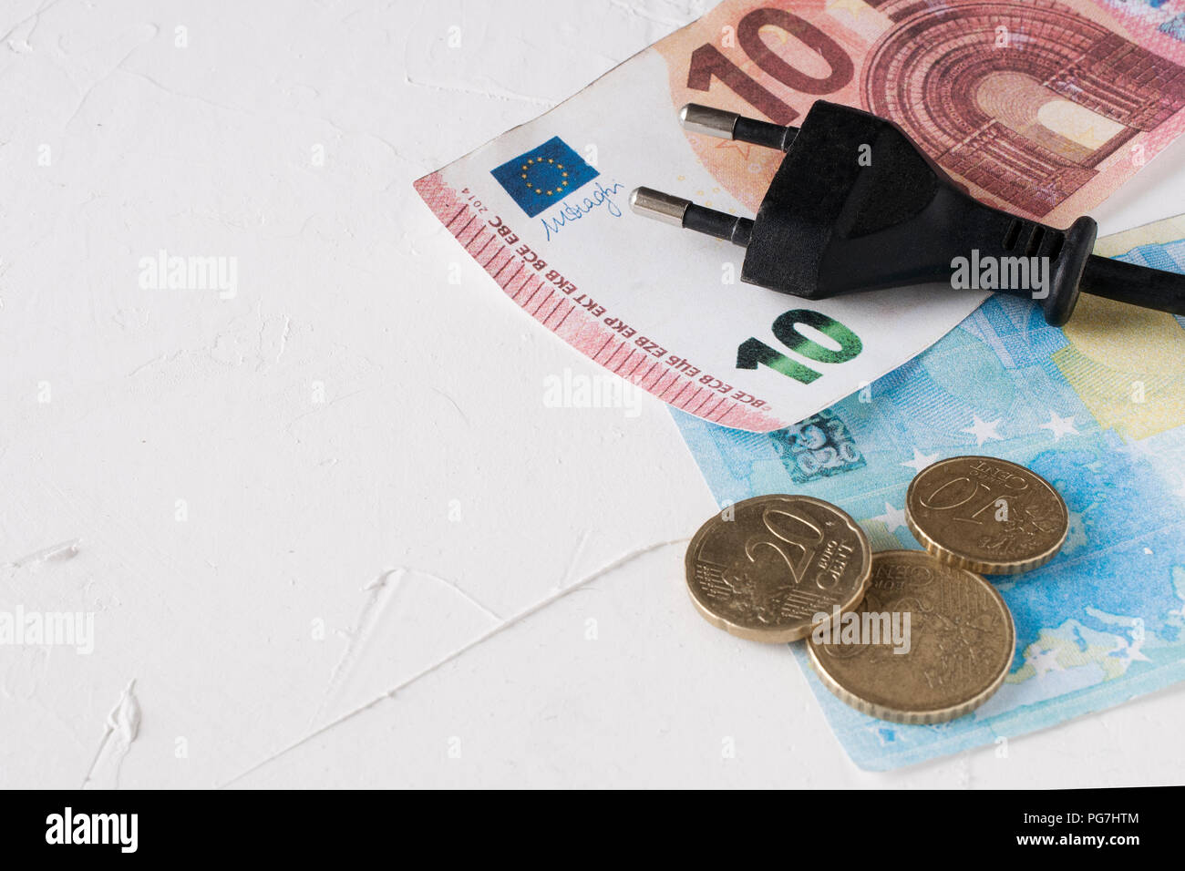Sparen bei der Stromrechnung Konzept: Steckdose über Euro-Scheine und -Münzen Stockfoto