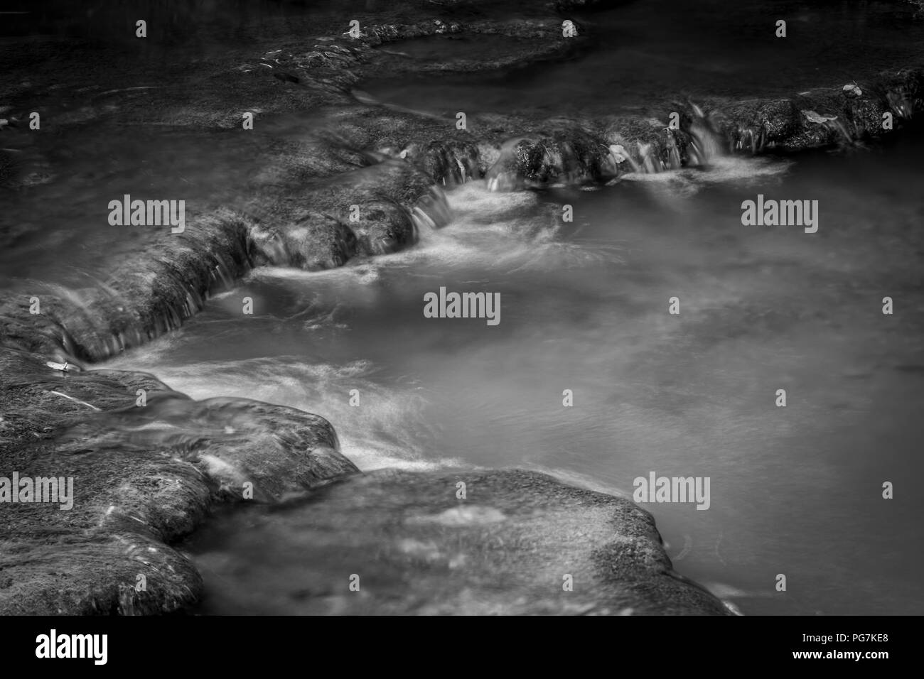 Schwarze und weiße Schuß des Flusses frisches Wasser fließt zu einem kleinen Teich in langen Belichtung Stockfoto