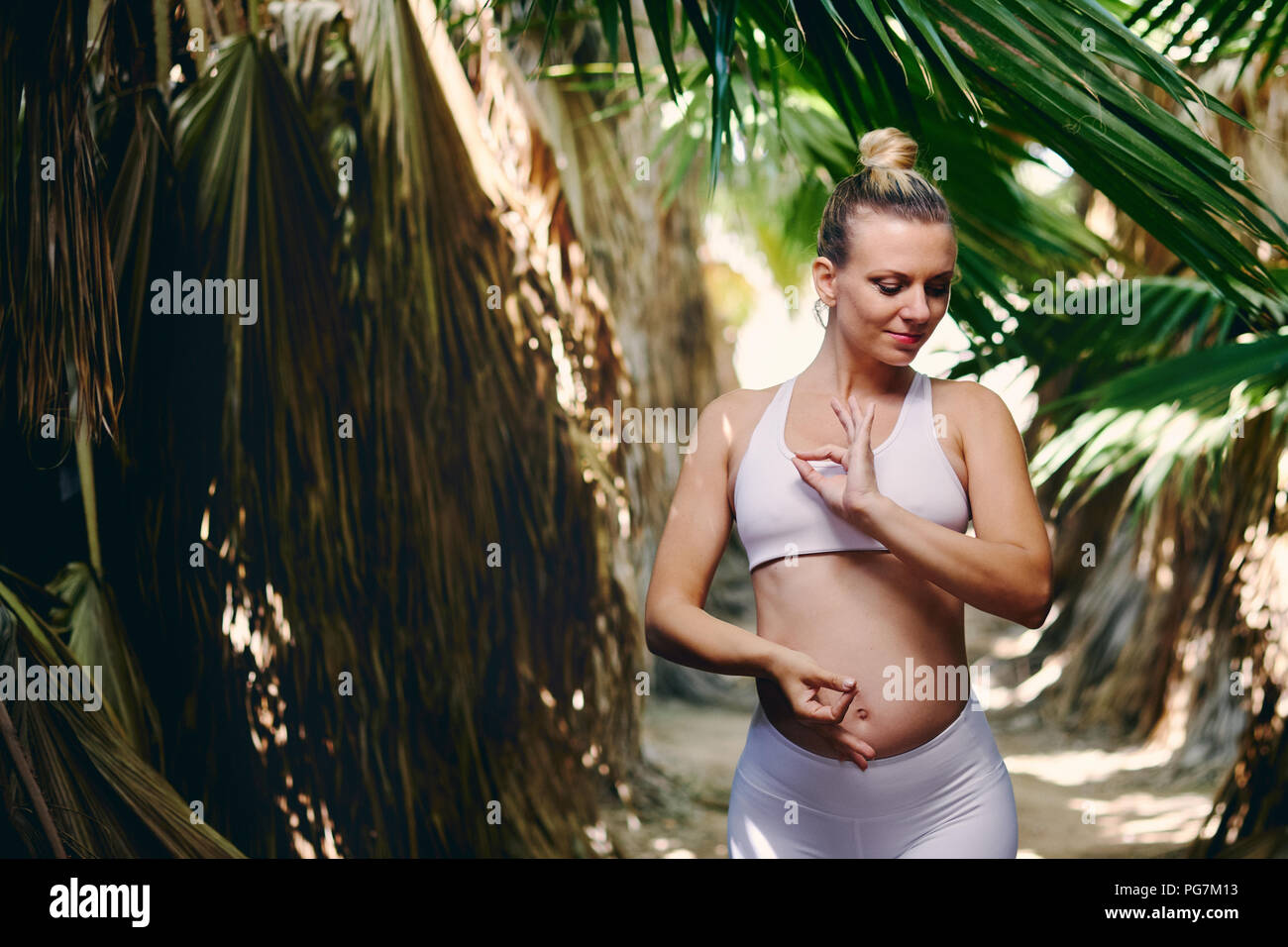 Junge attraktive blonde Frau in Weiß sportswear Yoga Pilates Fitness Übungen in der tropischen Natur. Pre natal trainieren, gesunden Lebensstil, rec Stockfoto