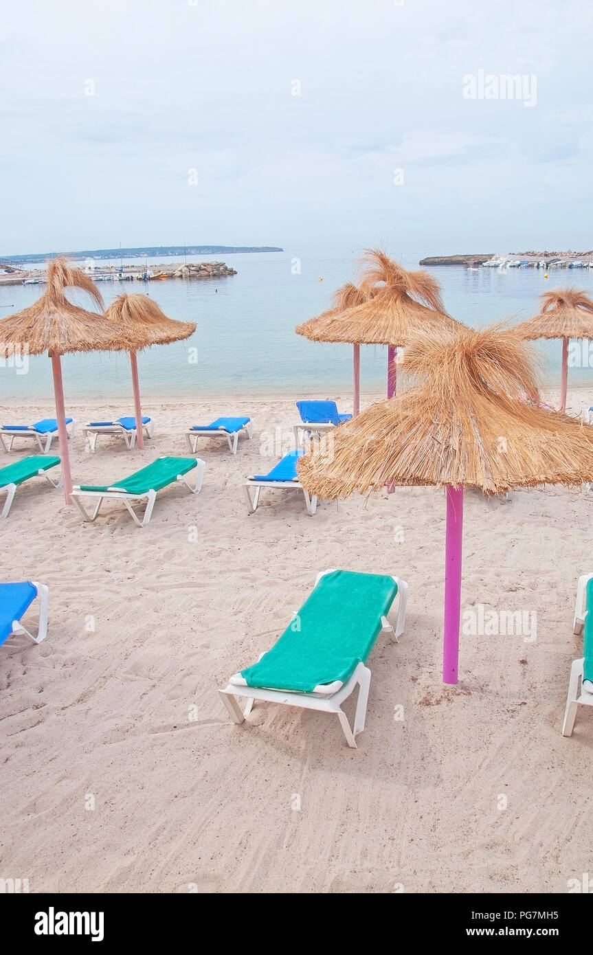 Leere Liegestühle und bunten Stroh Sonnenschirme auf Mallorca, Spanien. Stockfoto