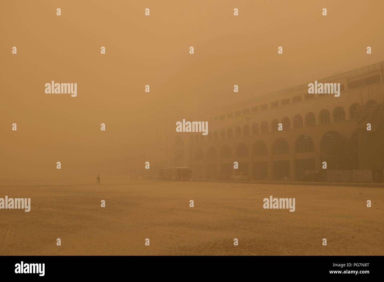 Menschen auf dem Weg zu den Mall of the Emirates, die kaum sichtbar ist, während ein Sandsturm in Dubai, Vereinigte Arabische Emirate Stockfoto