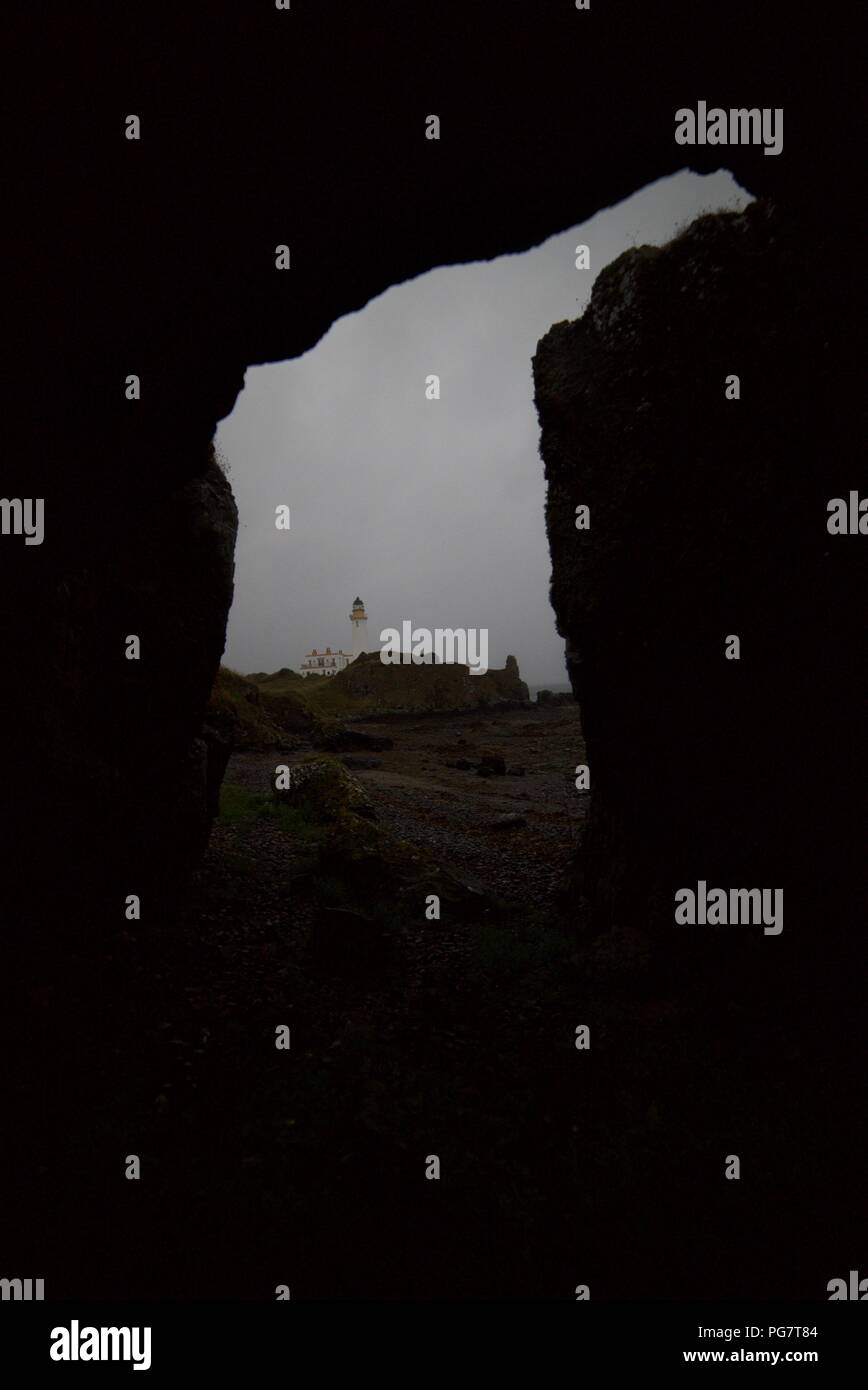 Leuchtturm gesehen aus einer Höhle an einem felsigen Strand (Turnberry Leuchtturm) (Ayrshire) Stockfoto