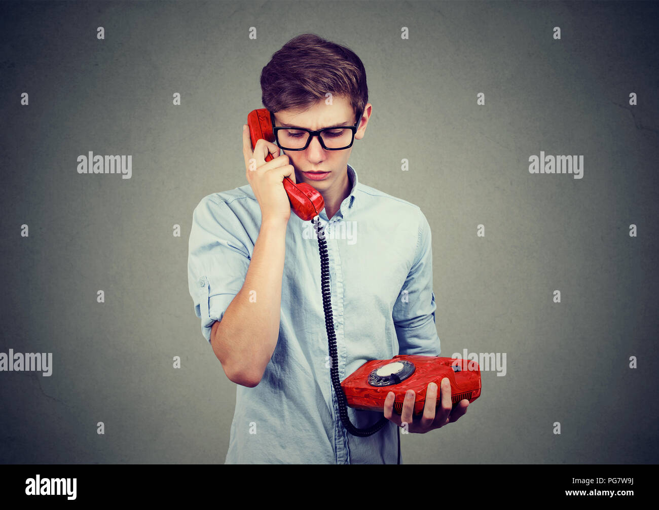 Traurig sorgen Jugendlicher Mann, der gerade in einem altmodischen Telefon verwirrt Stockfoto