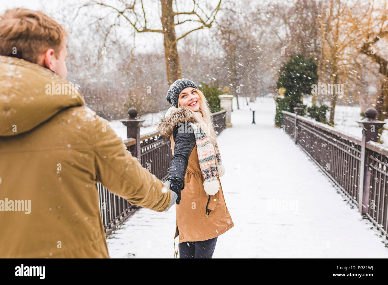 Portrait von Happy teenage stehendes Mädchen Hand in Hand mit ihrem Freund am Steg an einem verschneiten Tag Stockfoto