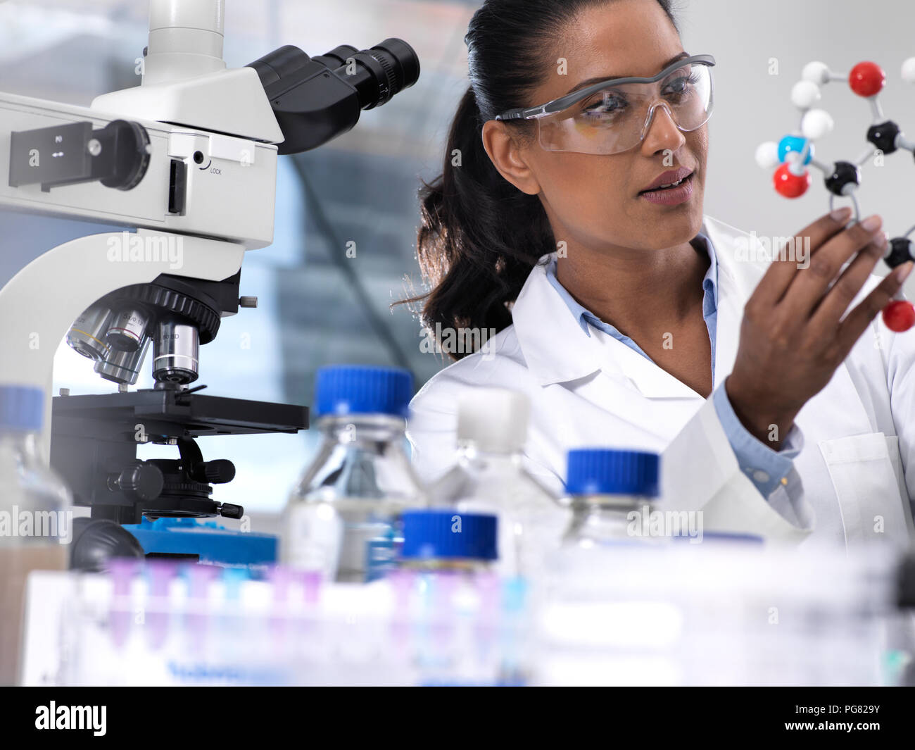 Die biotechnologische Forschung, Wissenschaftlerin der Prüfung einer chemischen Formel mit einem Ball und Stock molekularen Modell im Labor Stockfoto