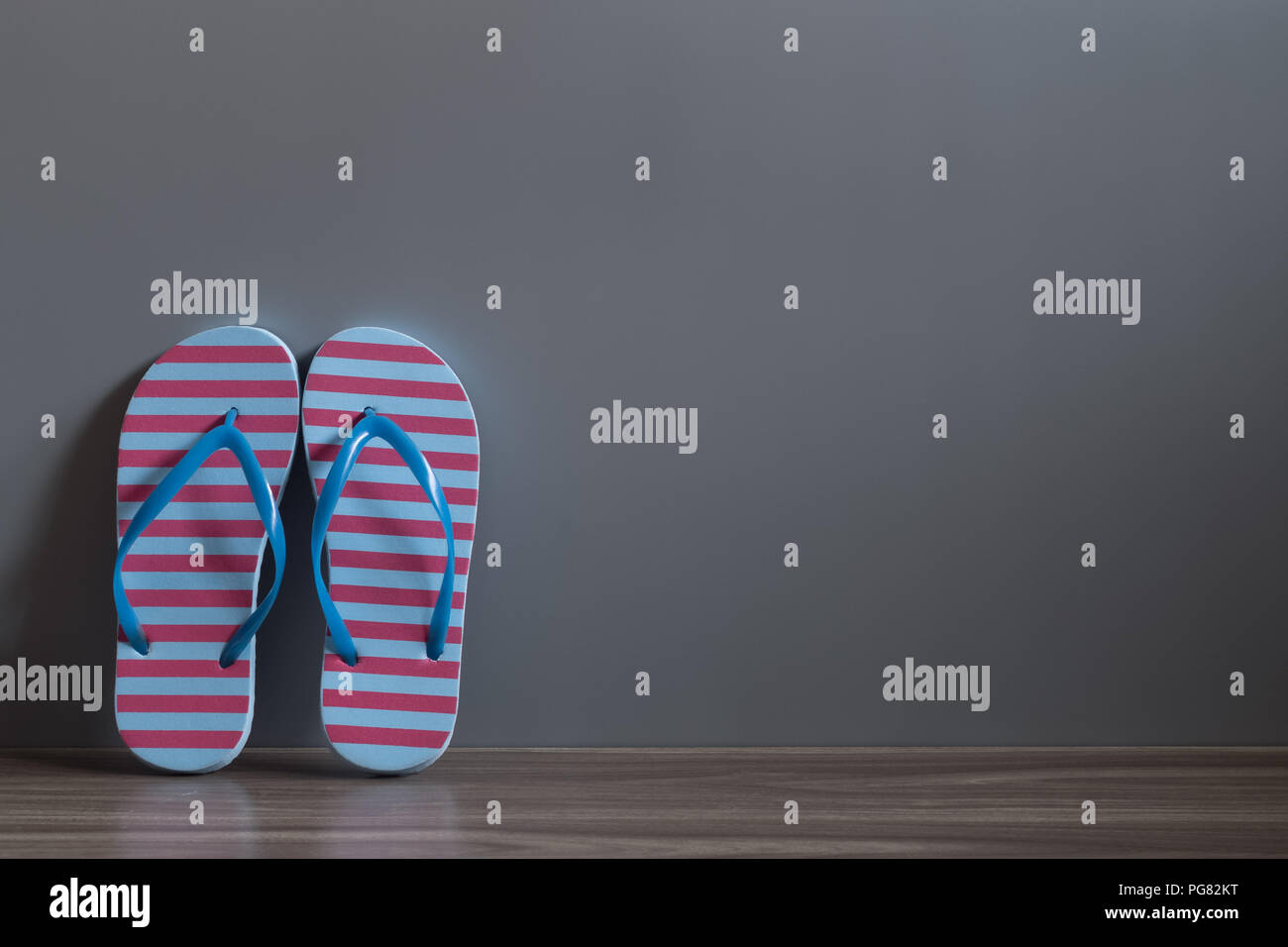 Rot und Blau Sandale Schuhe auf Holz Fußboden gegen die graue Wand. Gute Zeiten urlaub Frühling und Sommer Konzept zu erhalten. Stockfoto