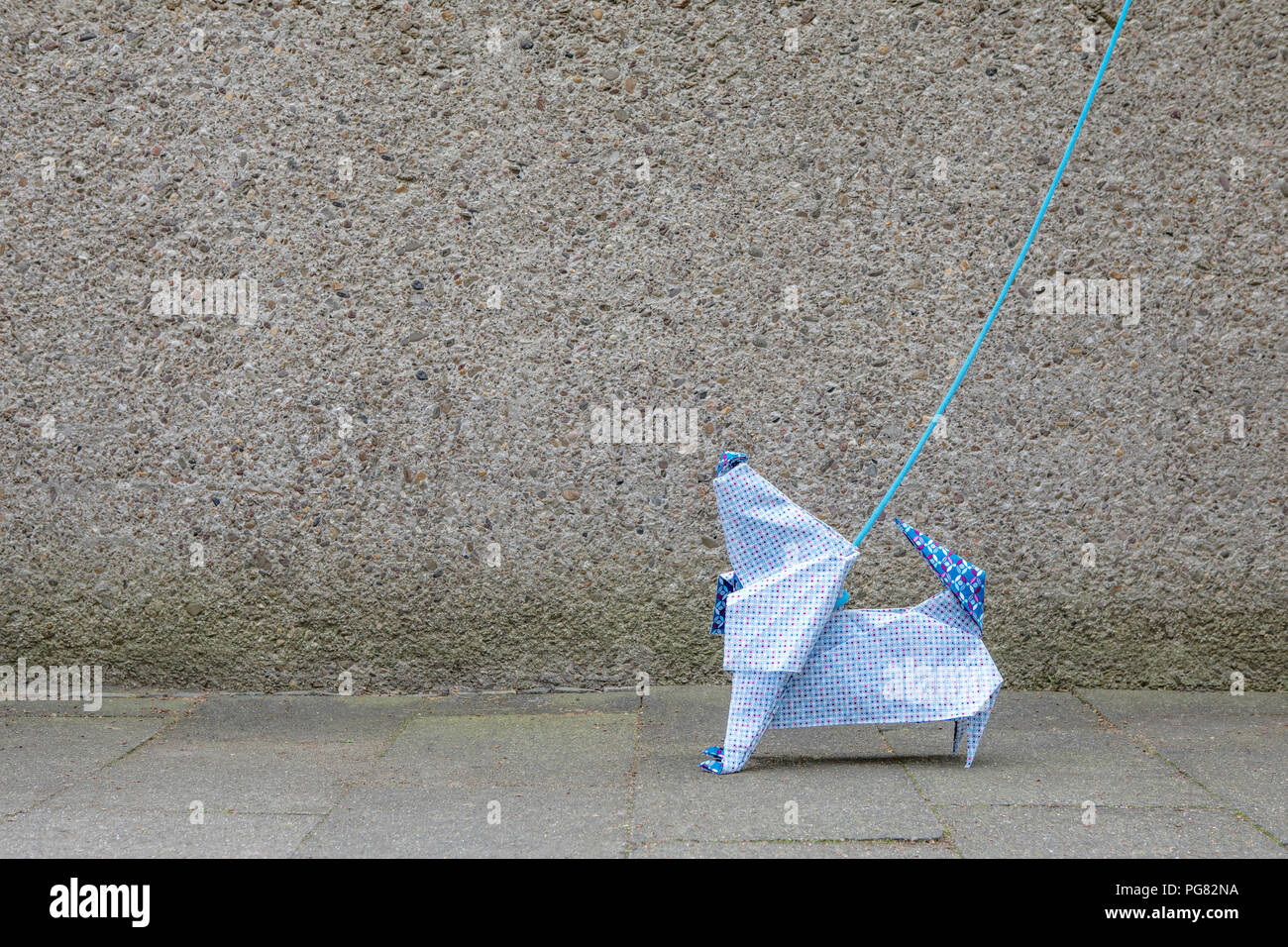 Origami Hund vor betonwand Stockfoto